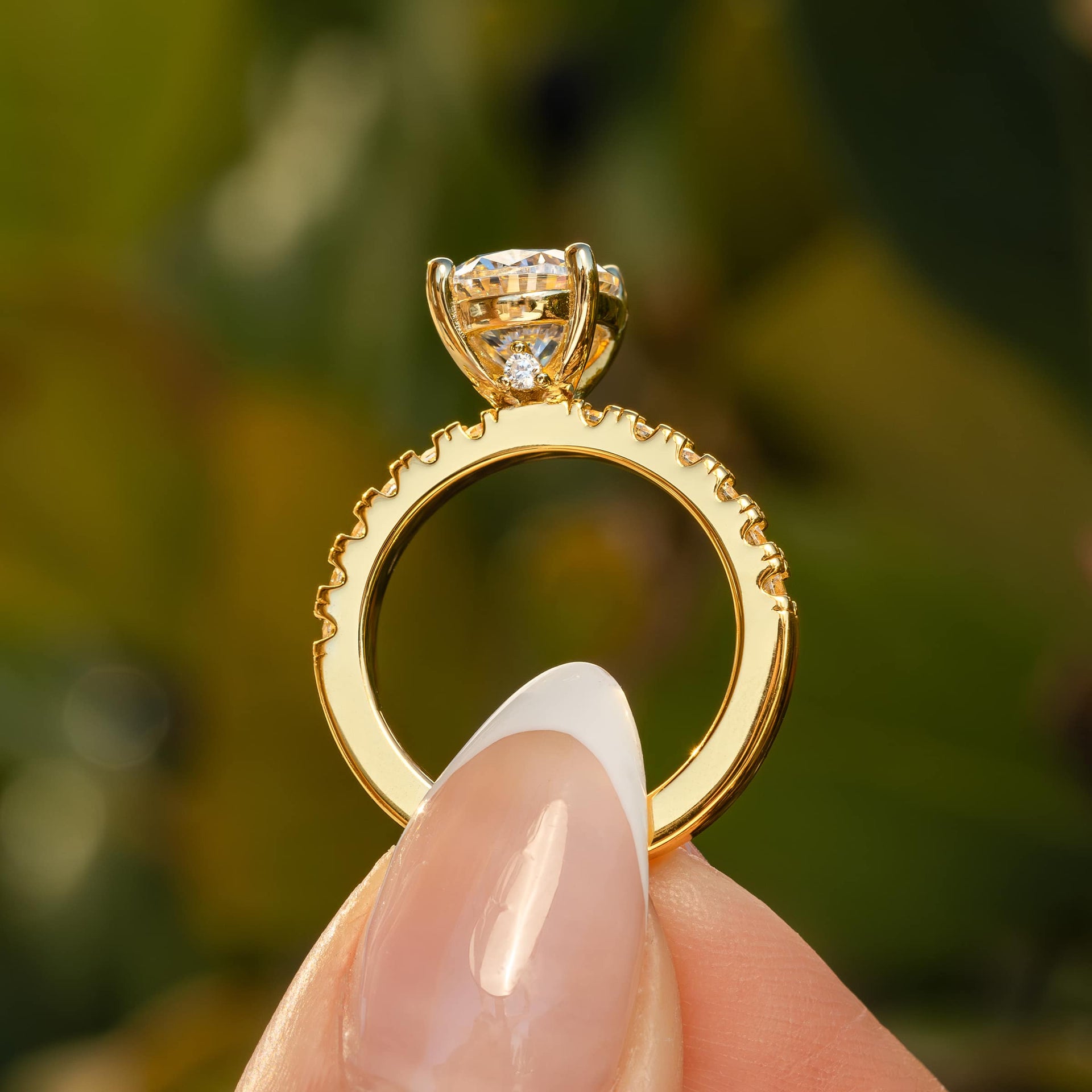 side view of gold oval engagement ring with view of hidden stone detail under its setting