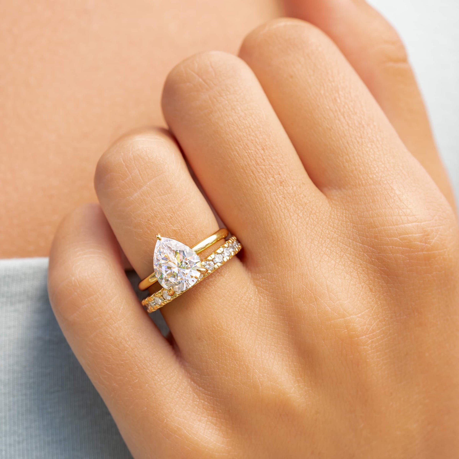 woman wearing gold pear engagement ring with elegant wedding band