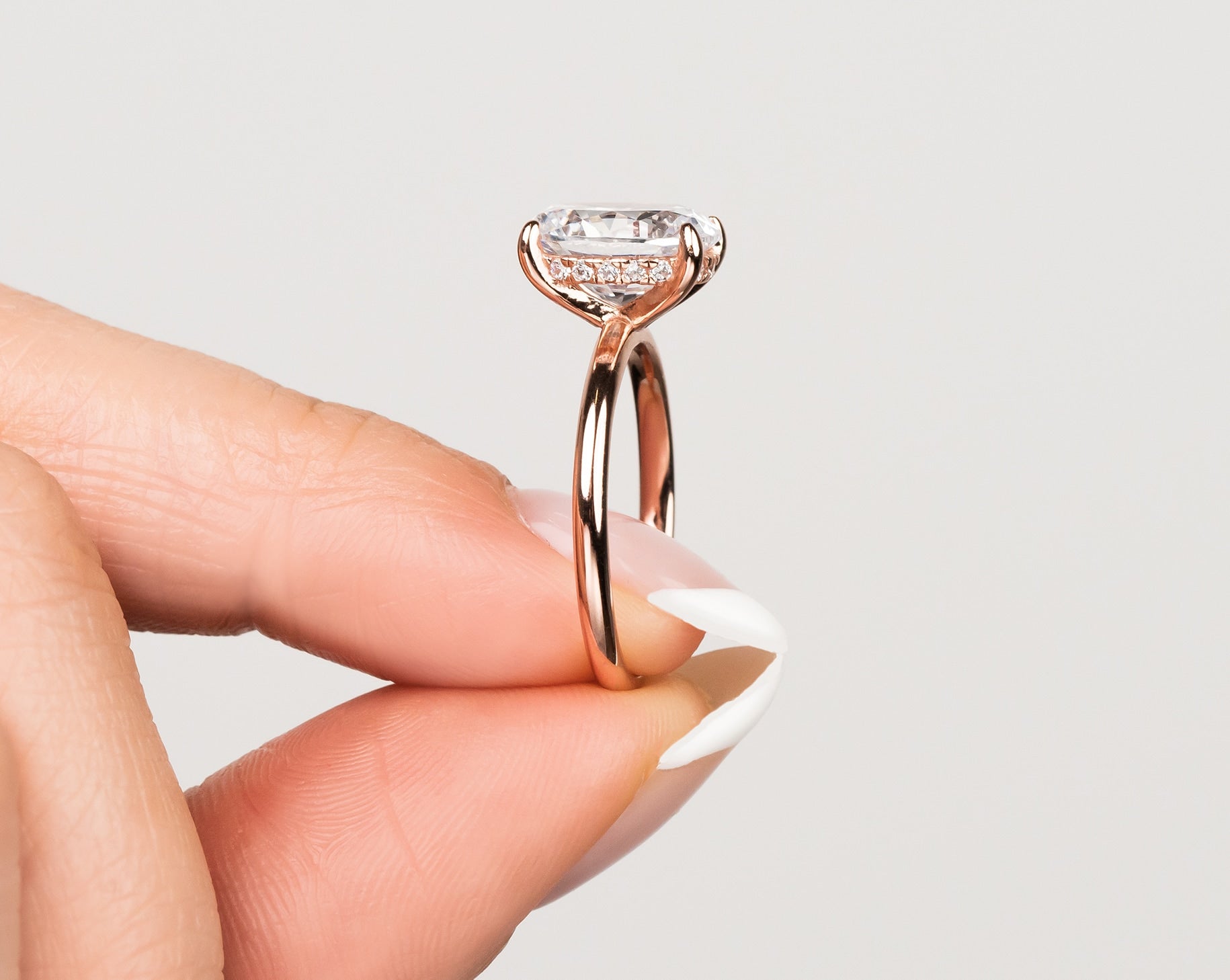 woman pinching rose gold engagement ring showing hidden halo