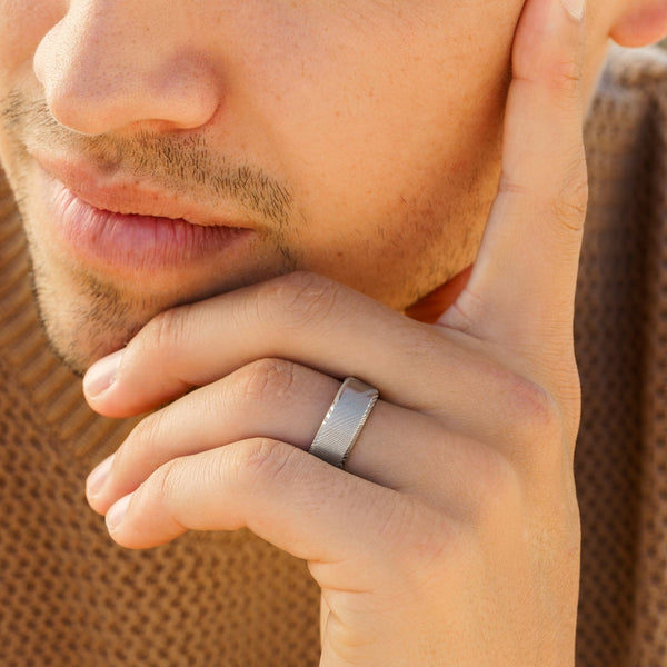 Sleek silver Damascus men's wedding ring on male hand