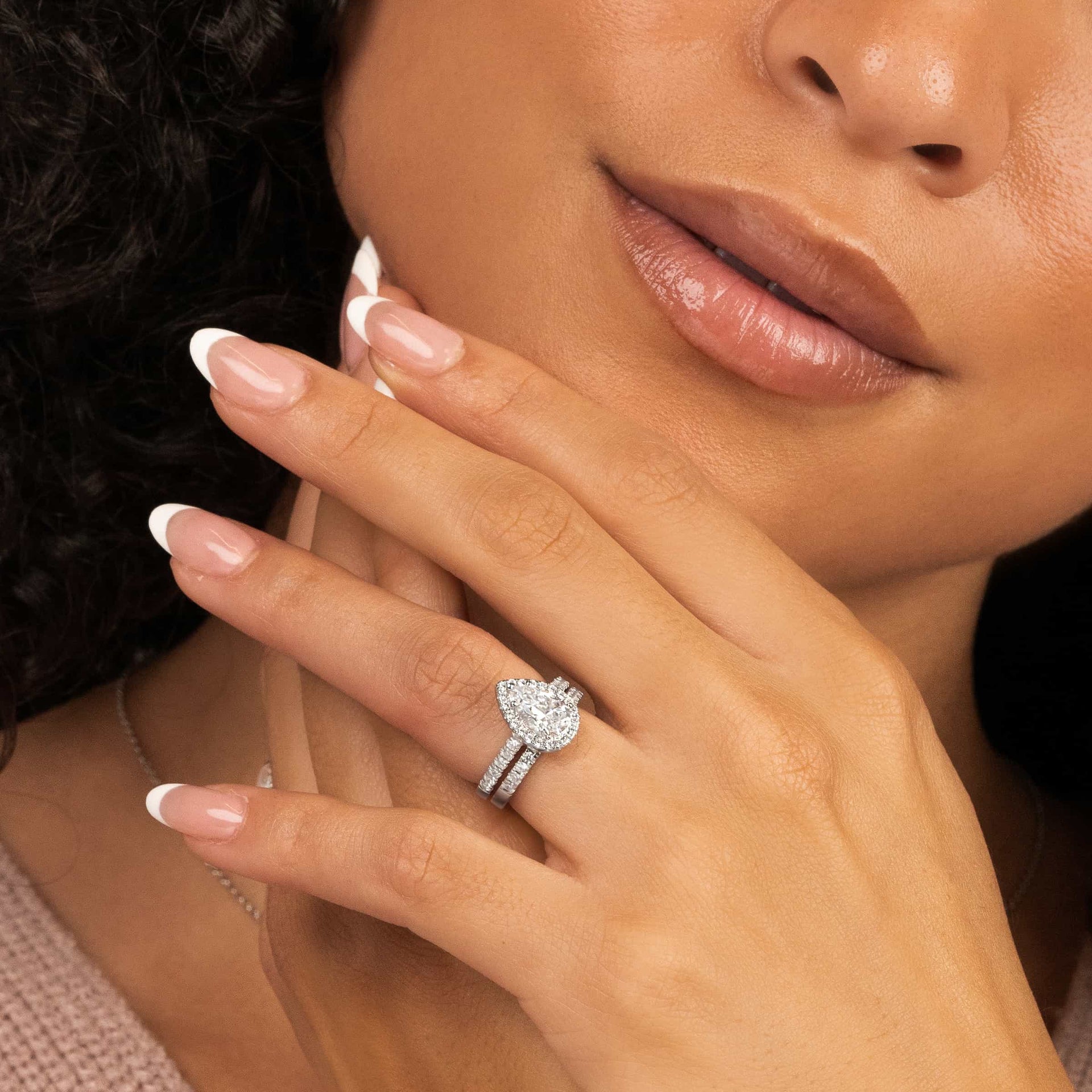 woman wearing silver wedding ring set with pink sweater