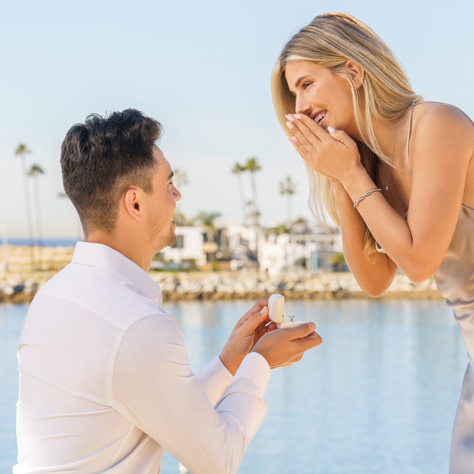 couple proposal with silver engagement ring in ring box by beach