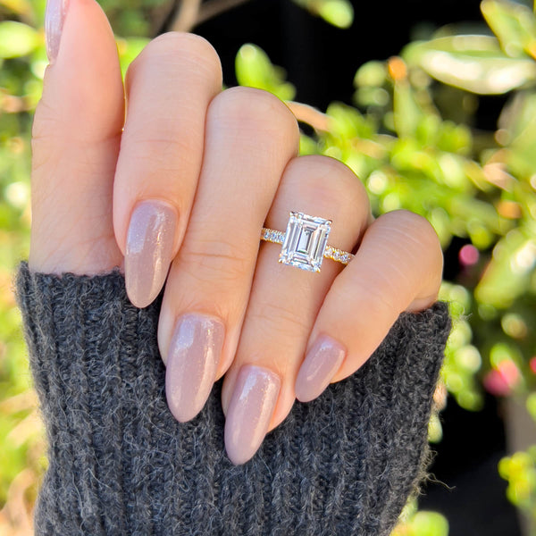 stunning gold emerald cut engagement ring on female hand in dark gray sweater