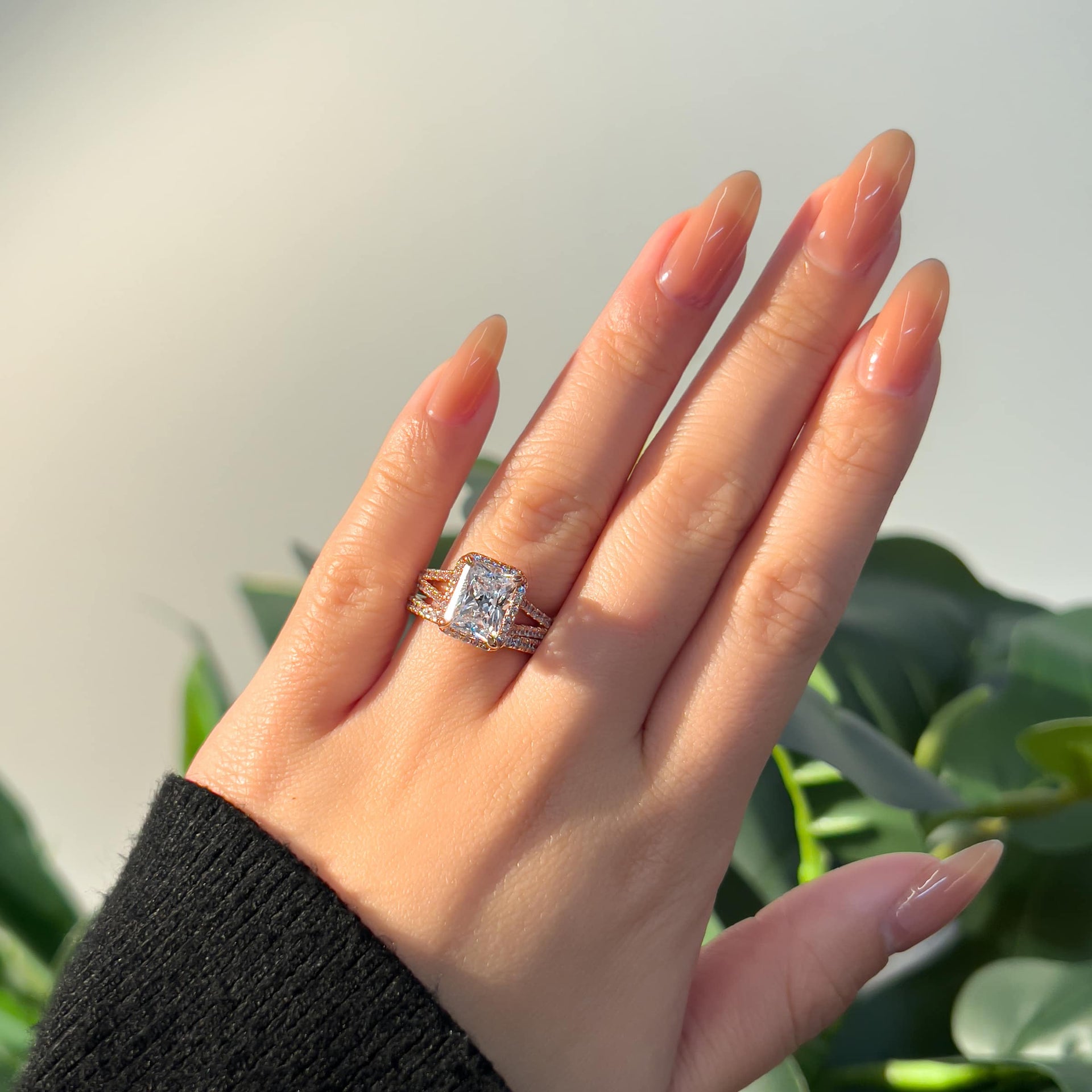 rose gold 3.5 radiant cut engagement ring with halo and split shank detailing, along with matching curved half eternity band on female hand