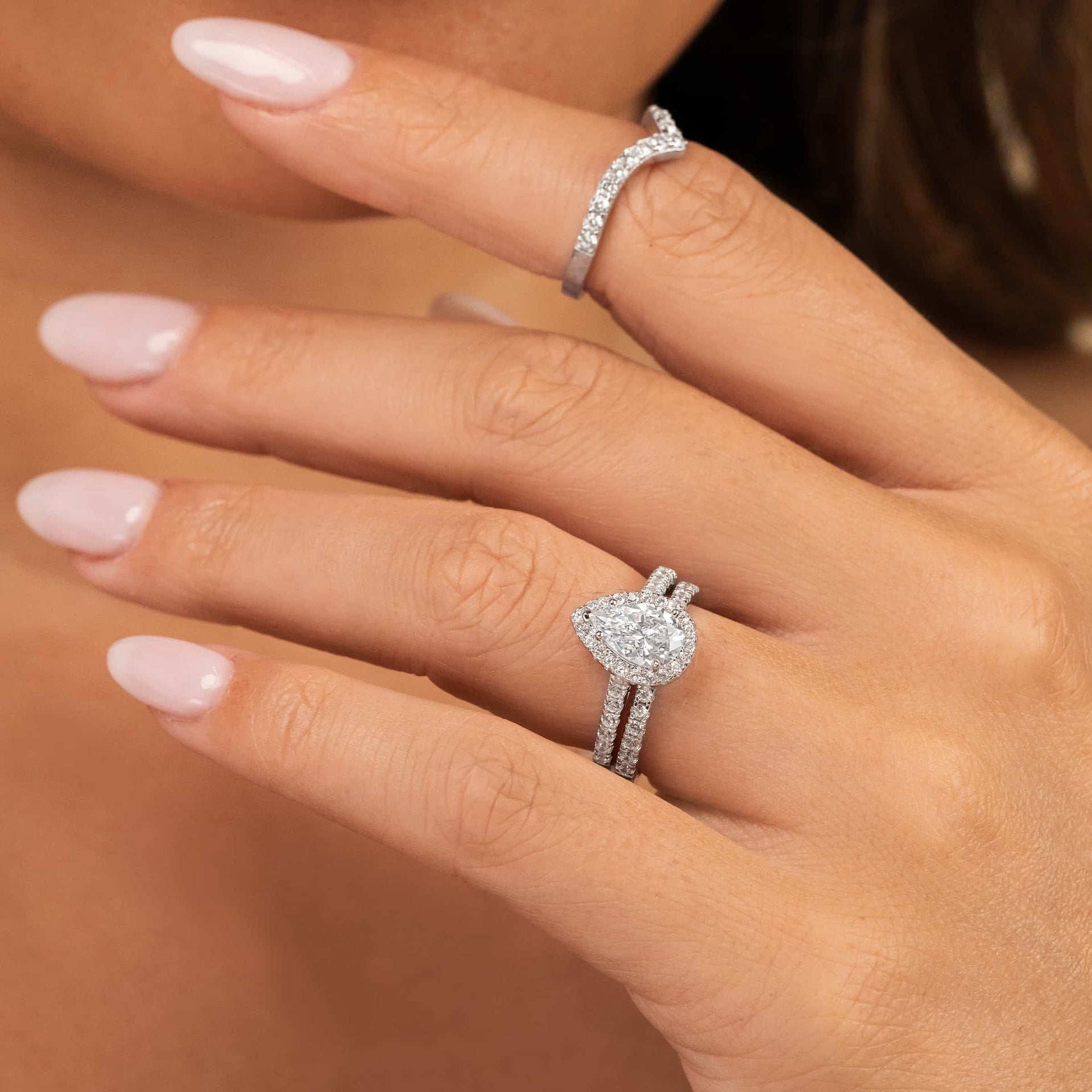 girl wearing pear shaped engagement ring with wedding bands