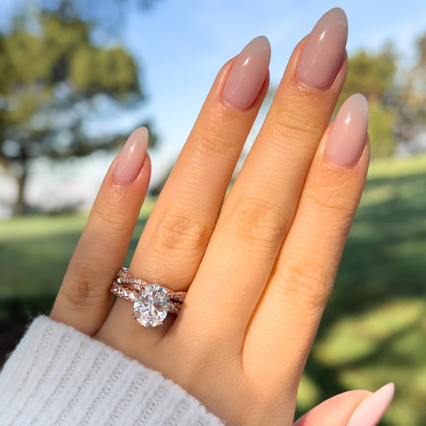 3 carat rose gold engagement ring paired with a vintage twisted detail wedding band modeled on female hand with white sweater
