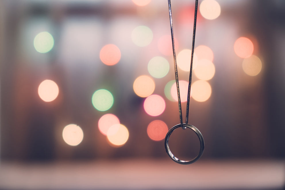a ring on a necklace against a background of blurred lights