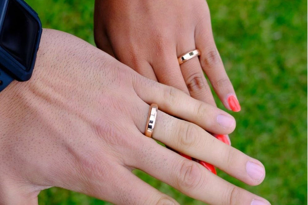 a close up of a couples hands wearing matching gold wedding bands