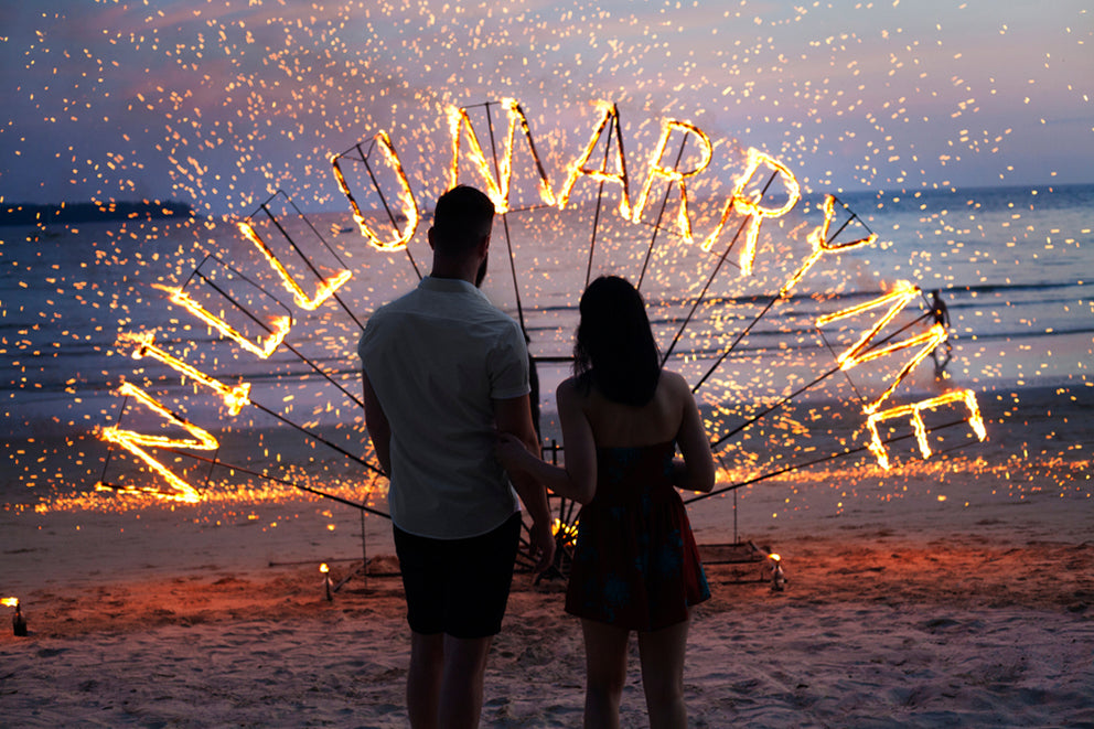 a couple at a surprise proposal sparkler marry me sign