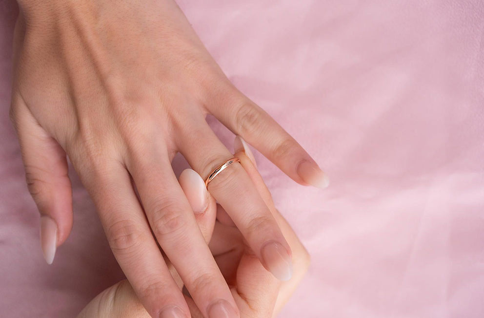 a woman putting on the always ring in rose gold