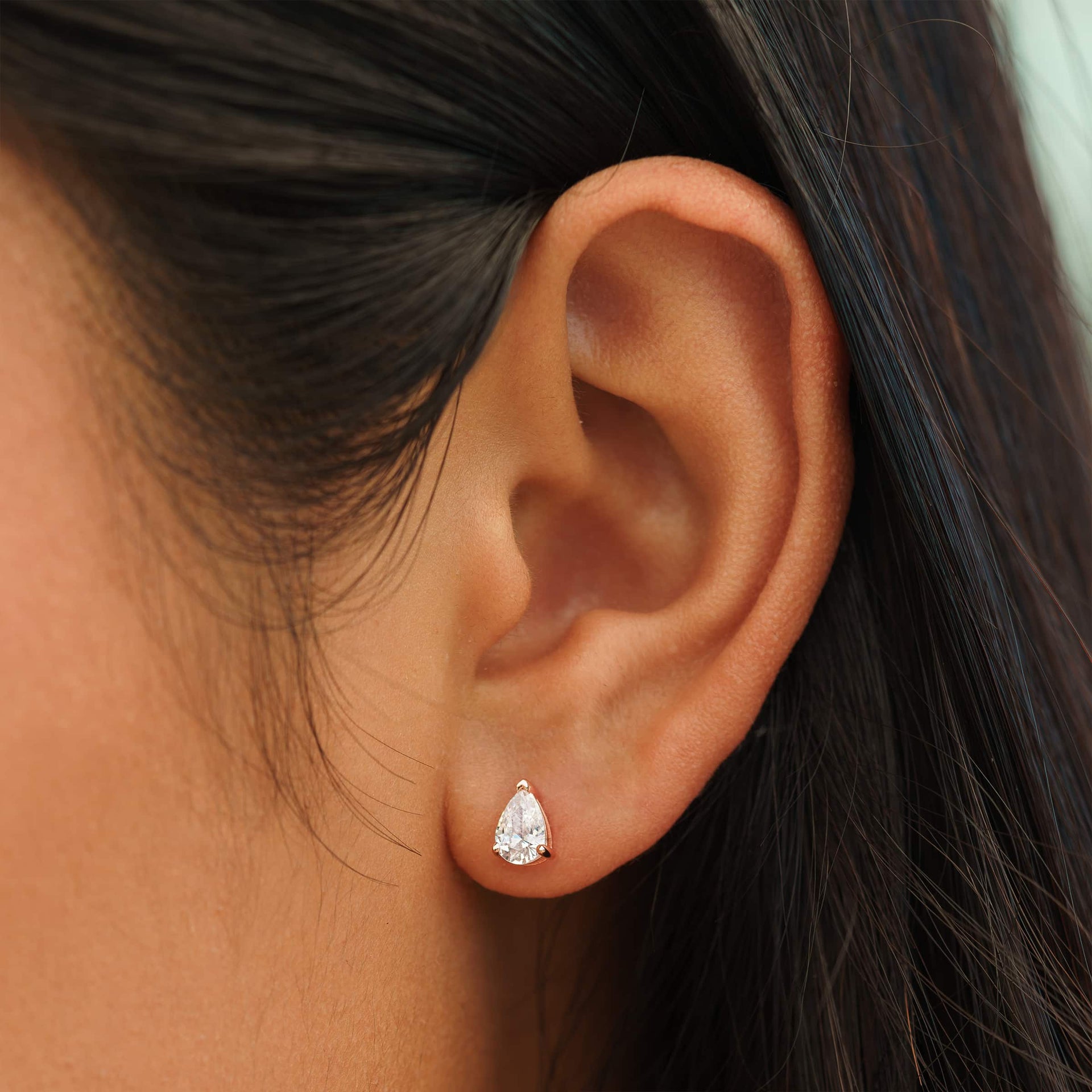 small rose gold pear cut stud earrings on female model