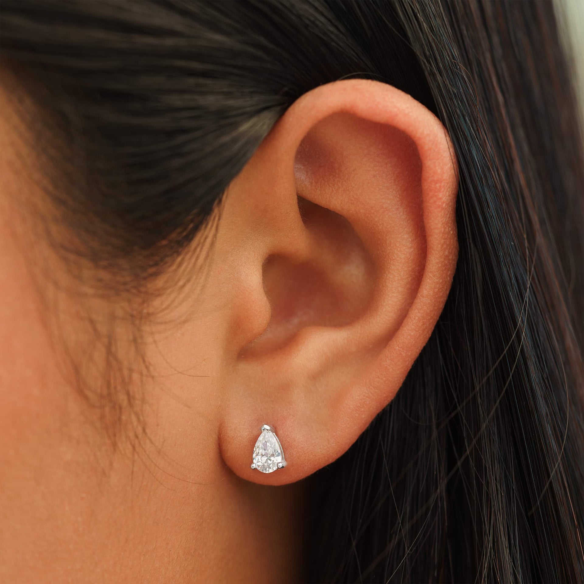 small silver pear cut stud earrings on female model