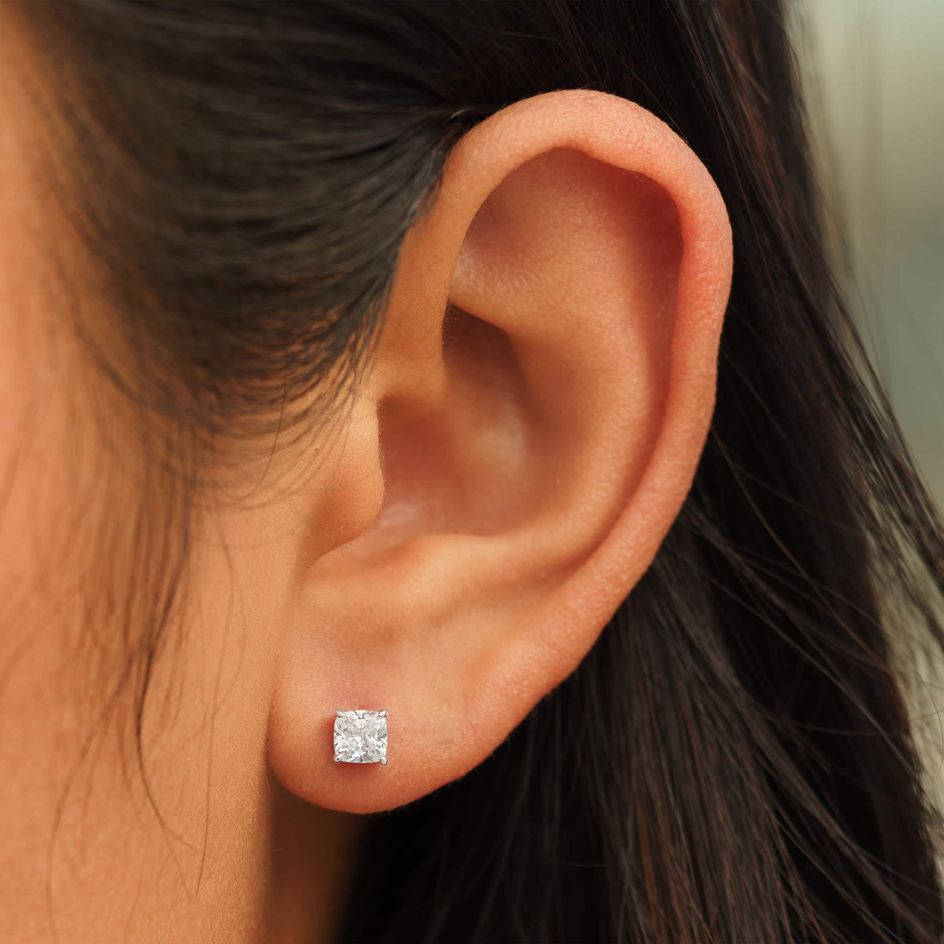 small silver cushion cut stud earrings on female model