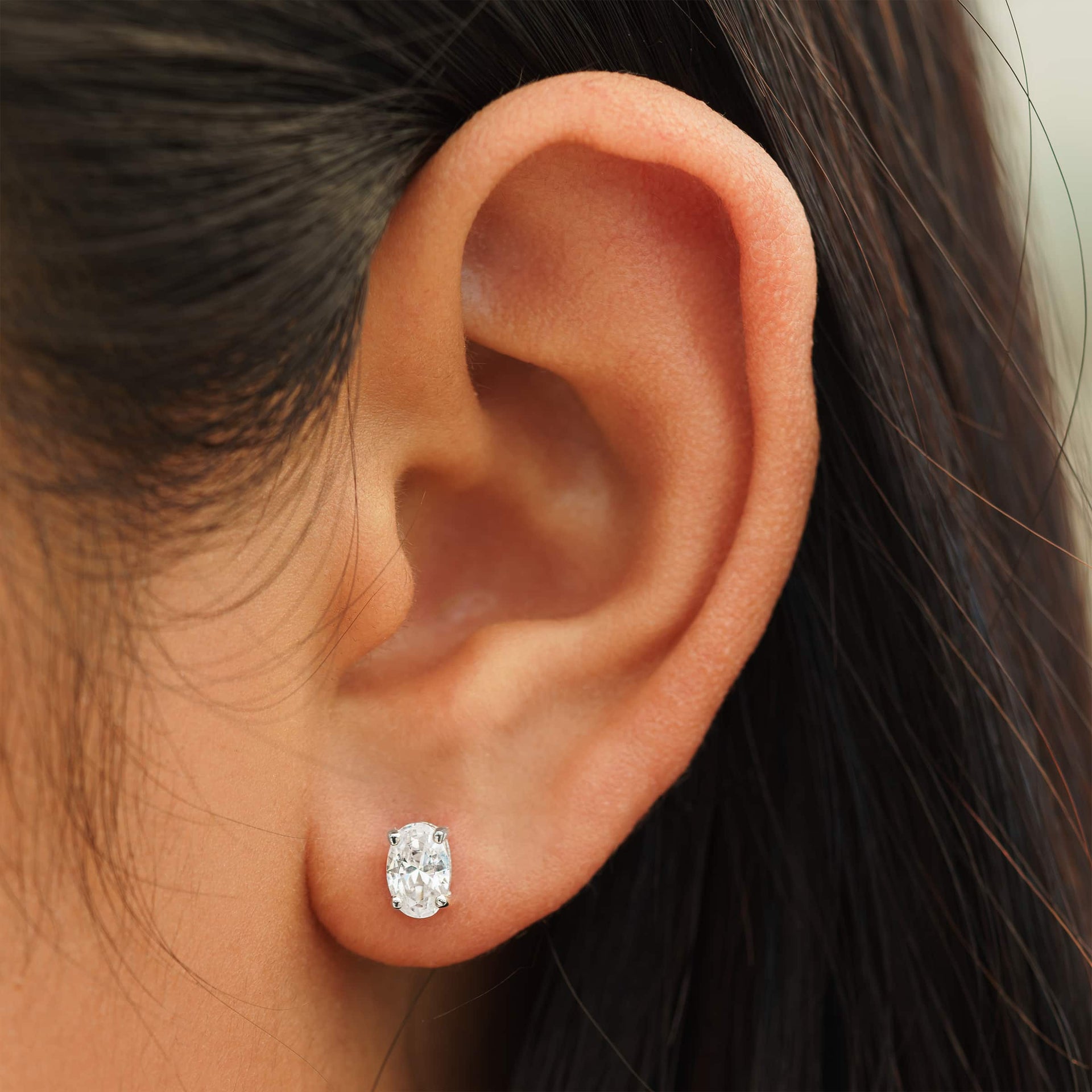 small silver oval cut stud earrings on female model