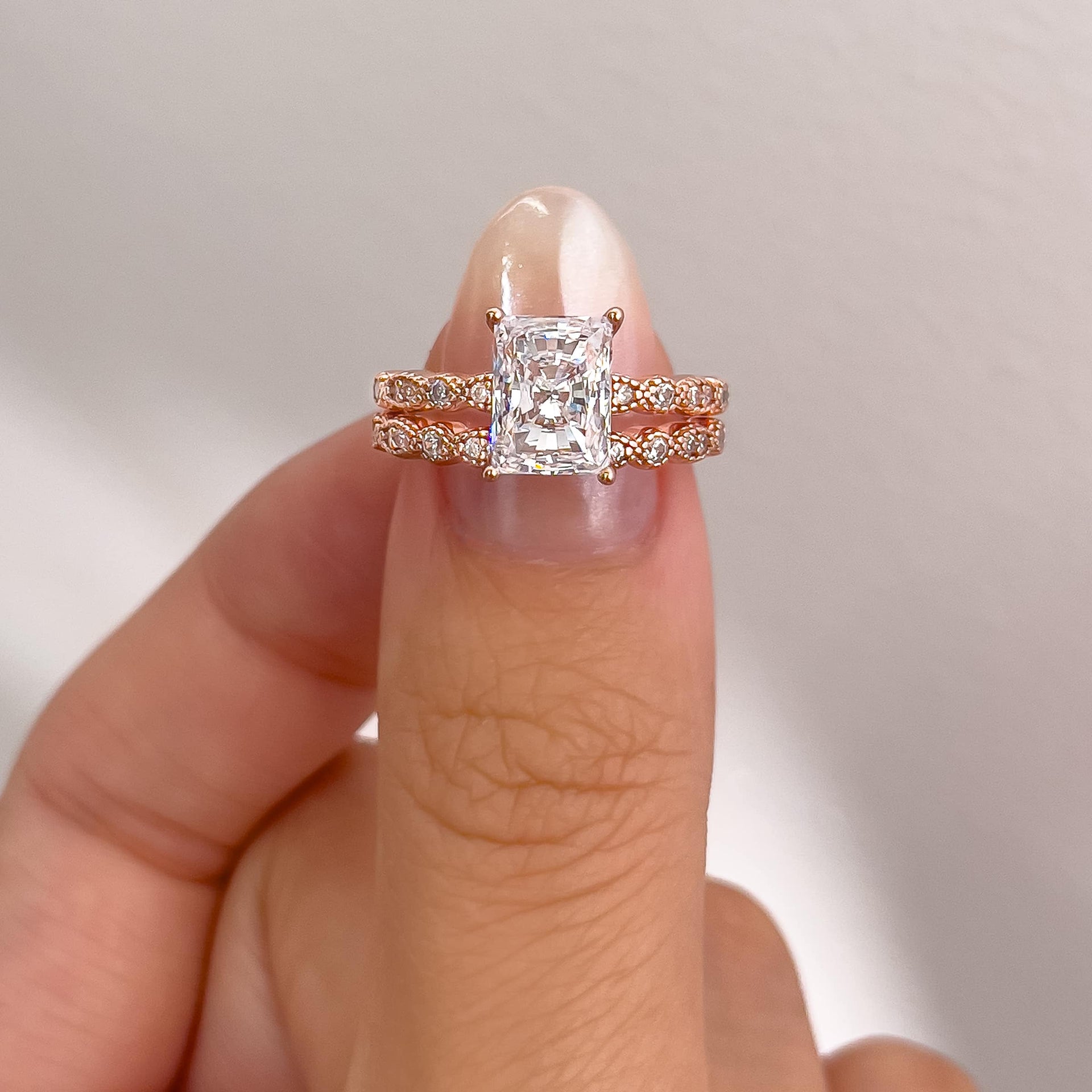 vintage rose gold radiant cut engagement ring paired with vintage rose gold wedding band on model with neutral nails