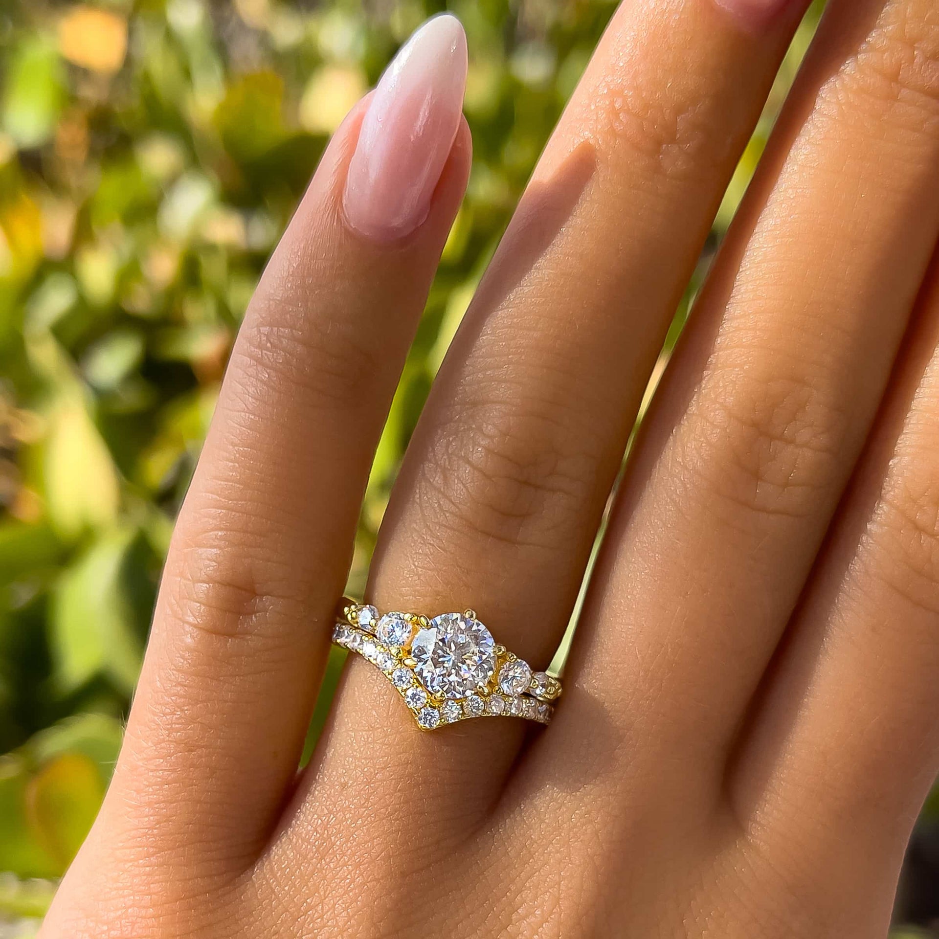 gorgeous gold wedding set made up of a gold vintage round cut engagement ring and gold chevron half eternity band on model with neutral nails