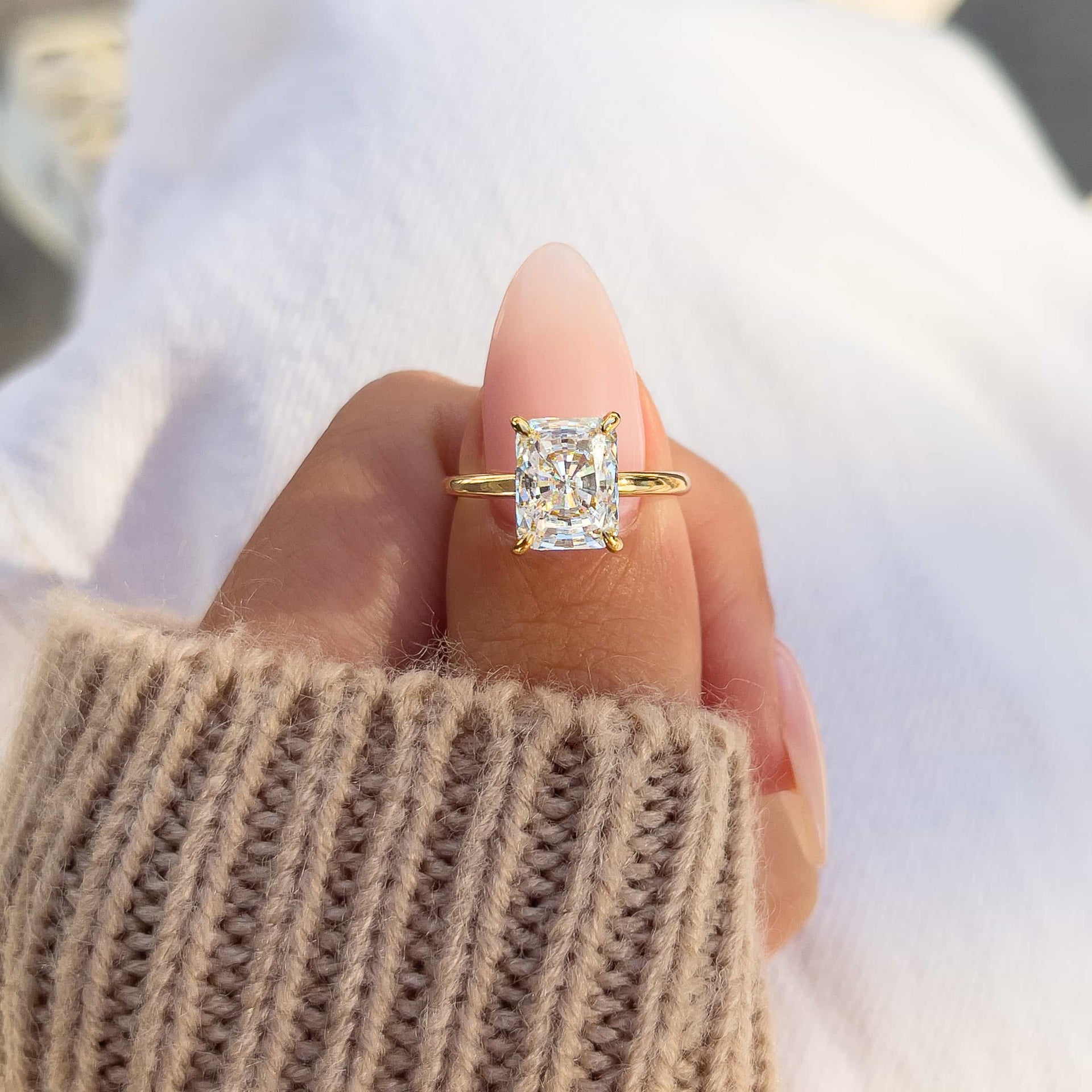 woman pinching beautiful gold radiant cut engagement ring