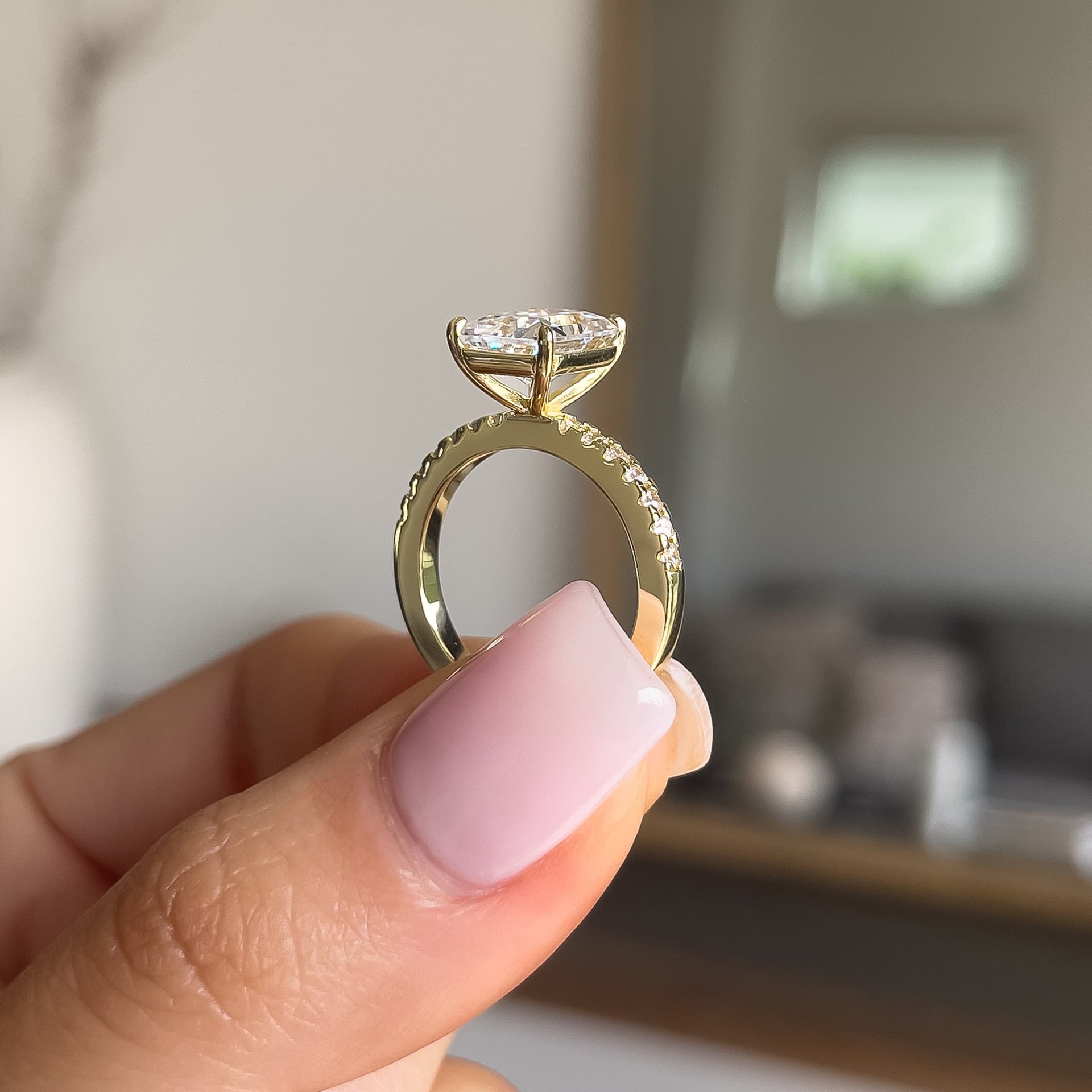Side profile of gold radiant cut engagement ring with half eternity band detailing with neutral background