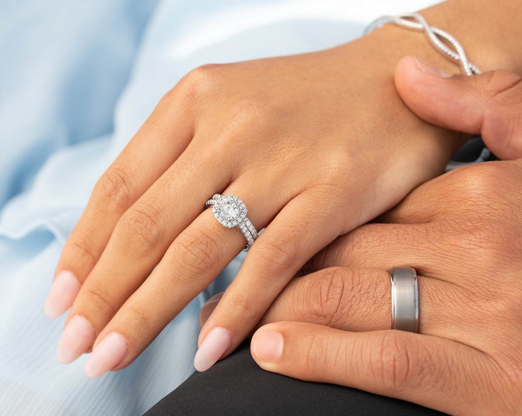 couple holding hands wearing silver engagement rings