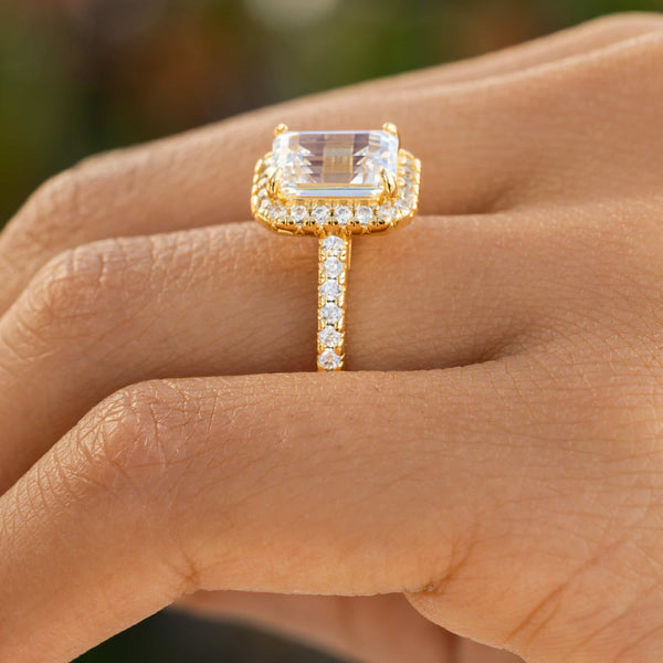 Close up gorgeous gold emerald cut engagement ring modeled on hand