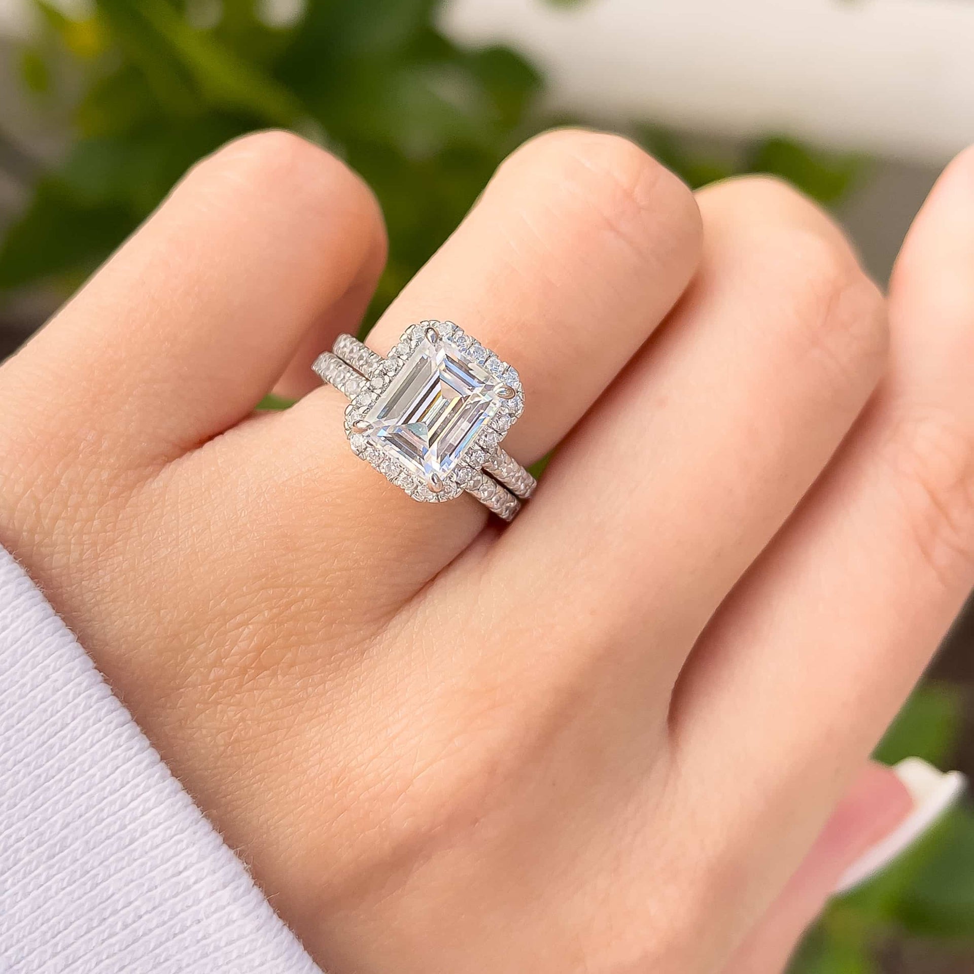 3 carat emerald cut engagement ring shown in silver paired with a stunning silver wedding band shown on model 