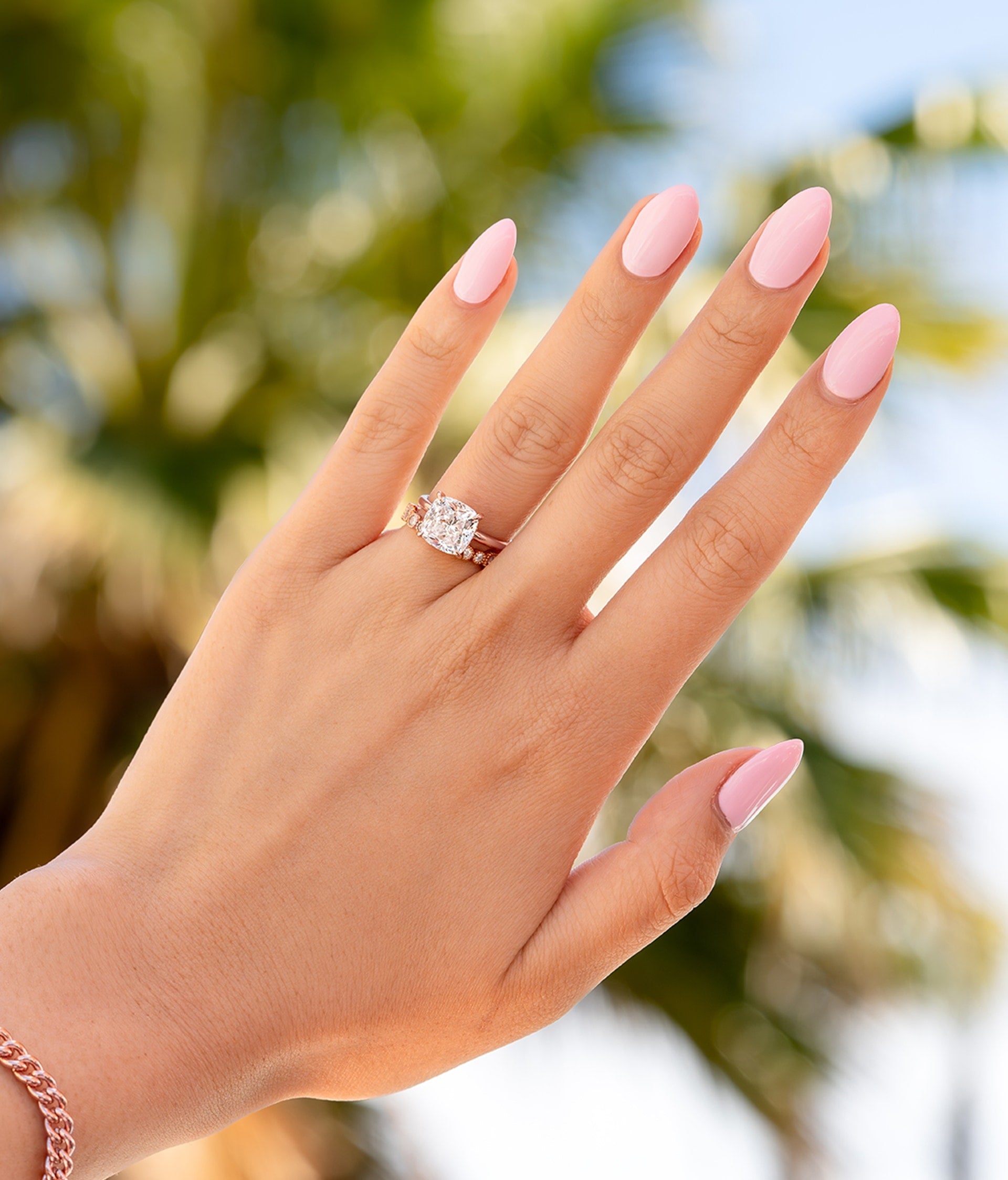 woman holding hands to palm tree wearing rose gold cushion engagement ring