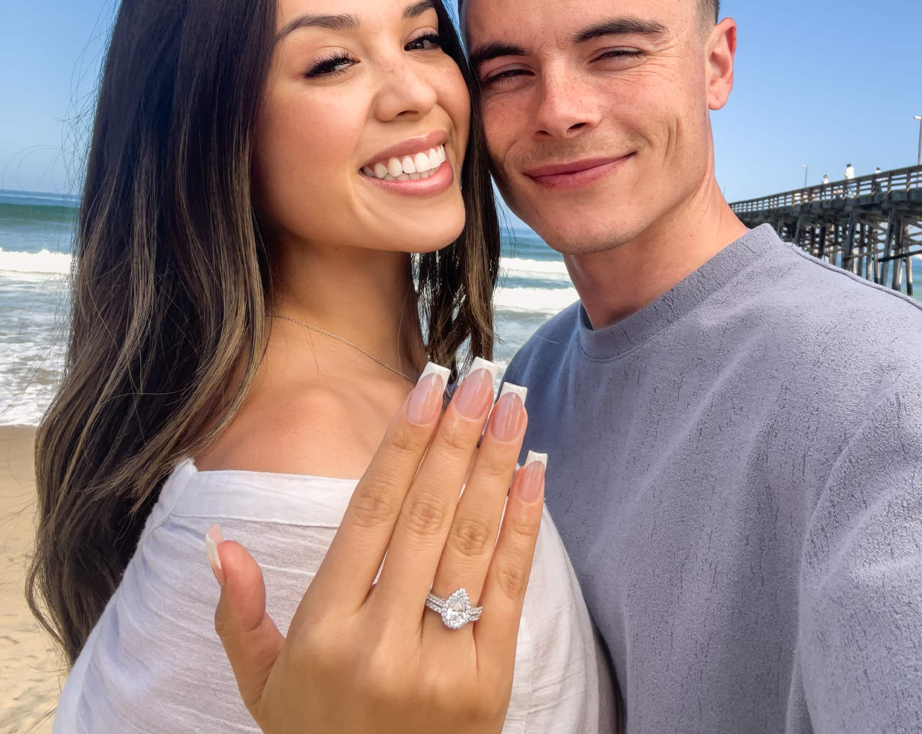 couple at beach wearing pear wedding ring set