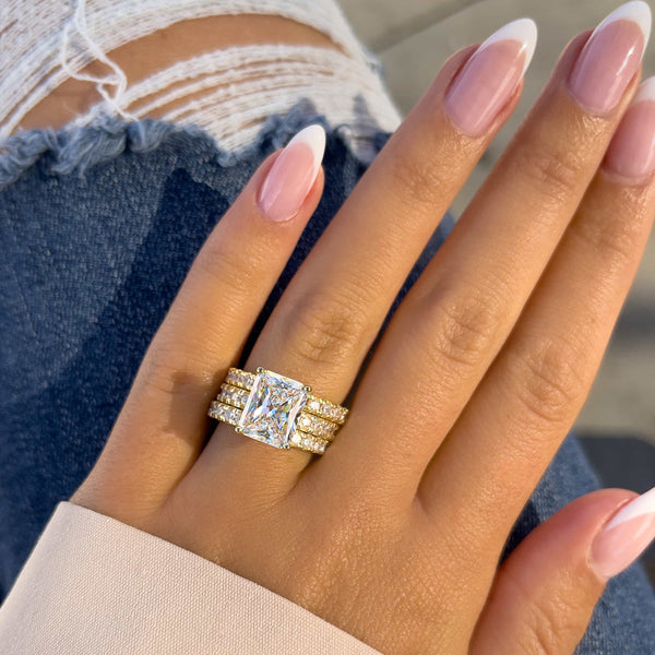 thick gold eternity wedding bands paired with stunning gold radiant engagement ring on female hand with french tip nails and blue denim