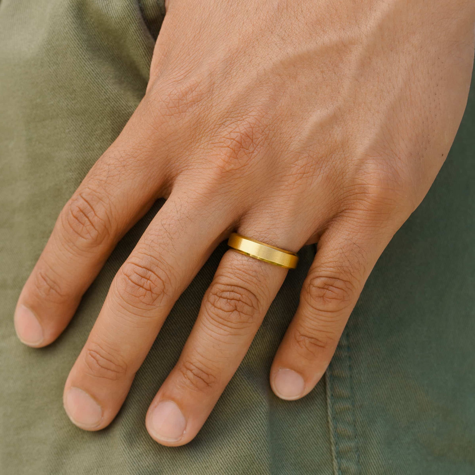 man wearing sleek gold wedding band with green pants