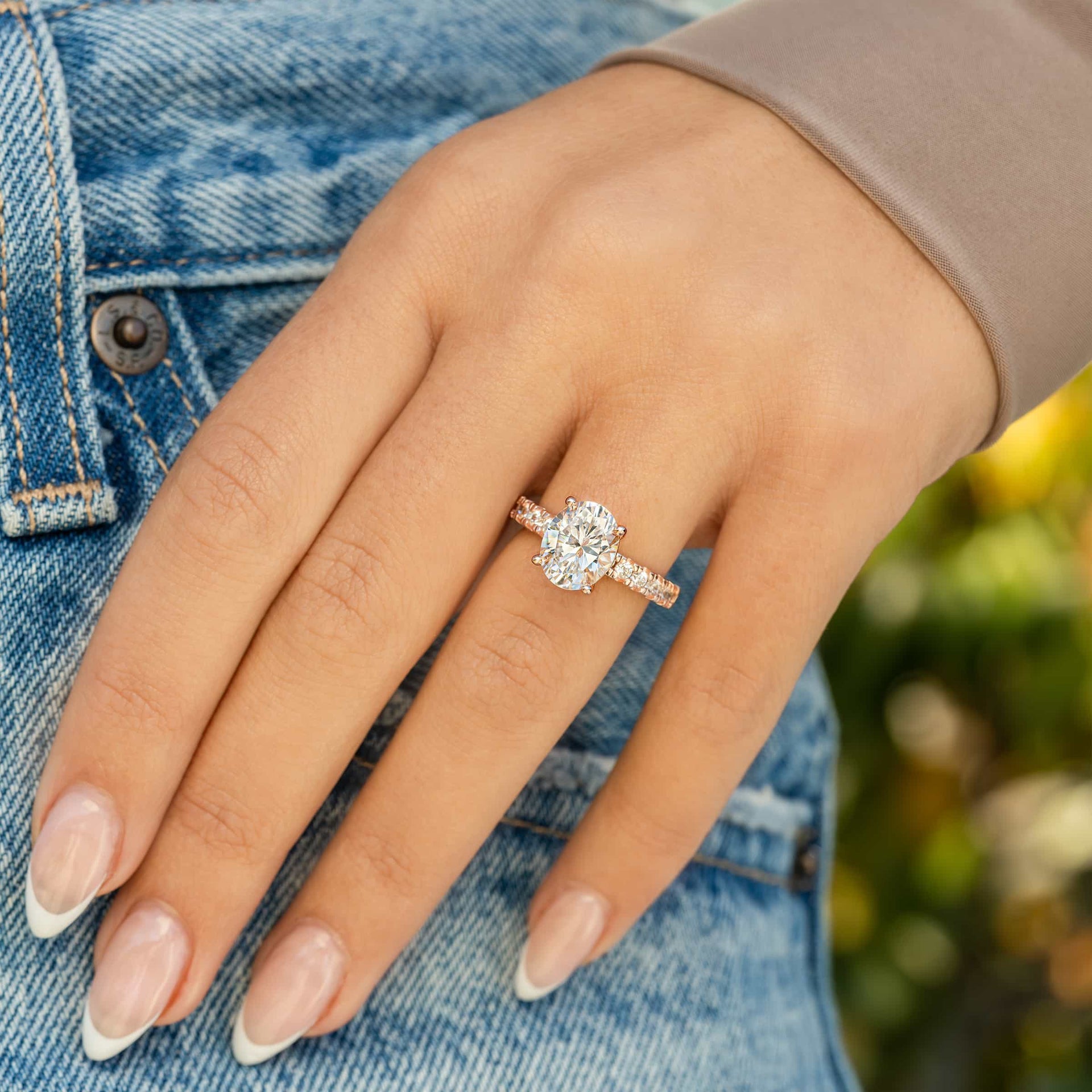 Dazzling rose gold oval cut engagement ring on female model with french tip nails