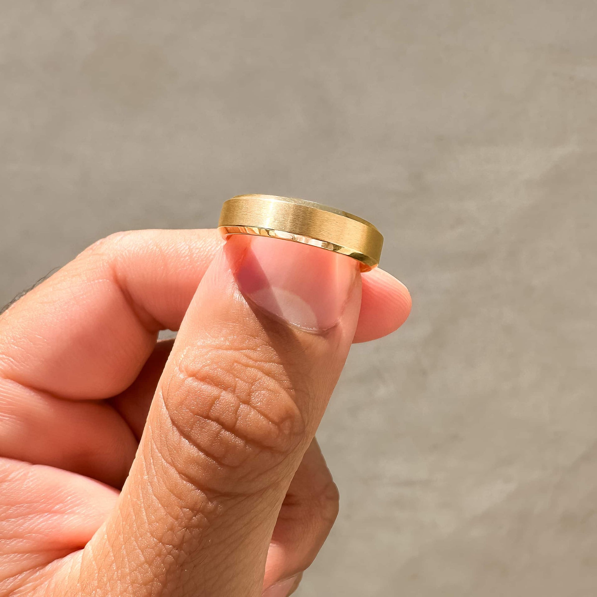 Man pinching gold chic wedding band with neutral background
