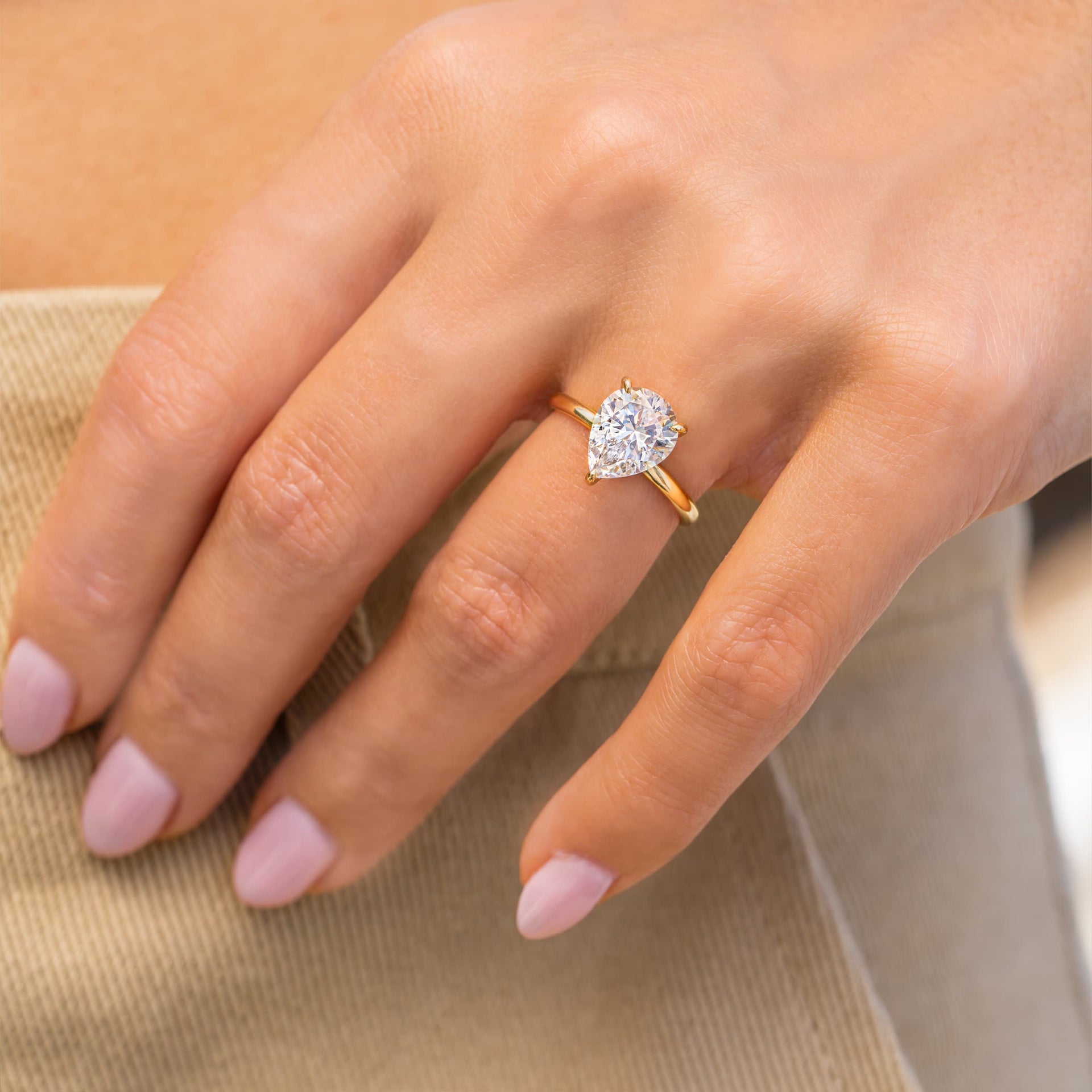 gold pear shaped engagement ring on woman's hand