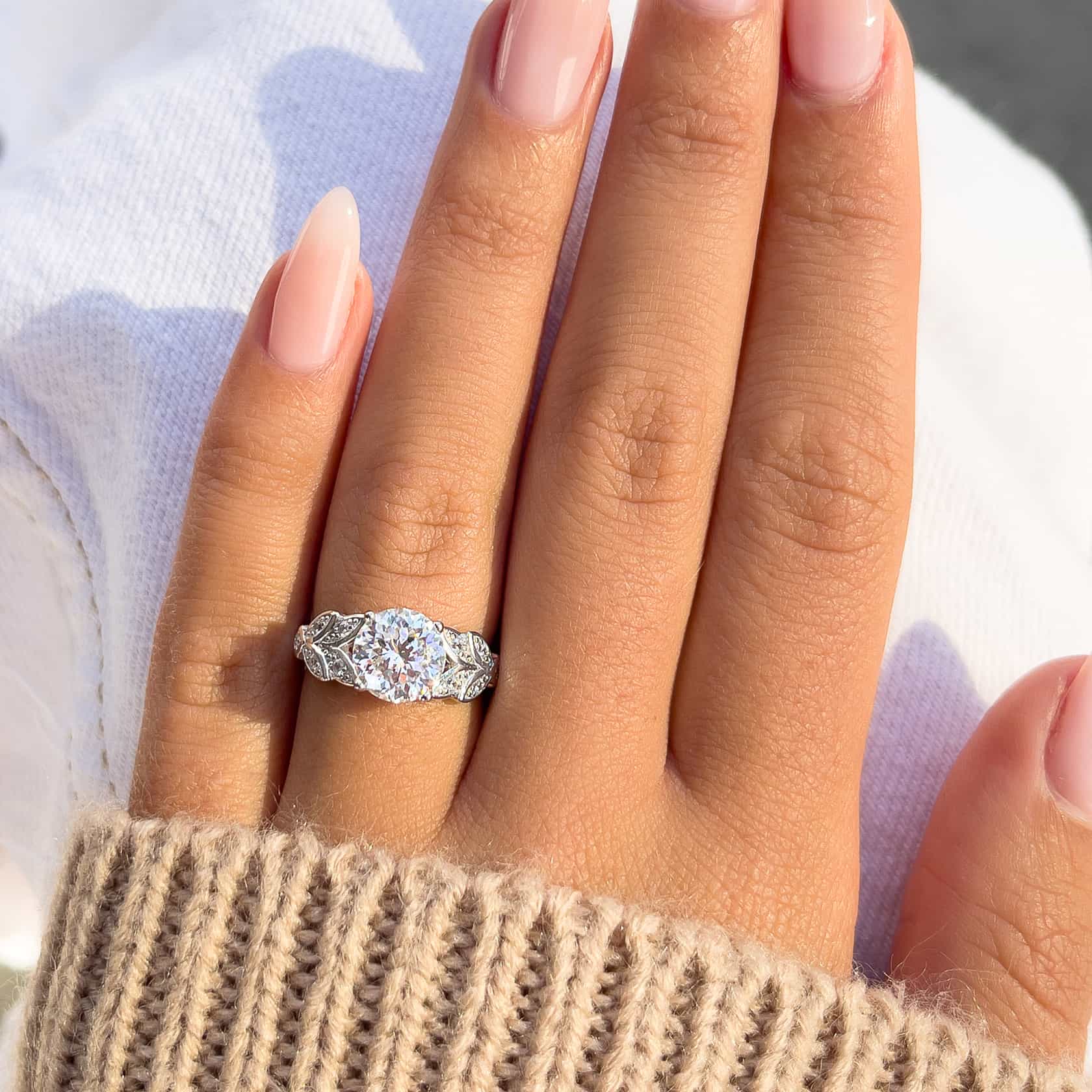 woman wearing silver meadow engagement ring with brown sweater