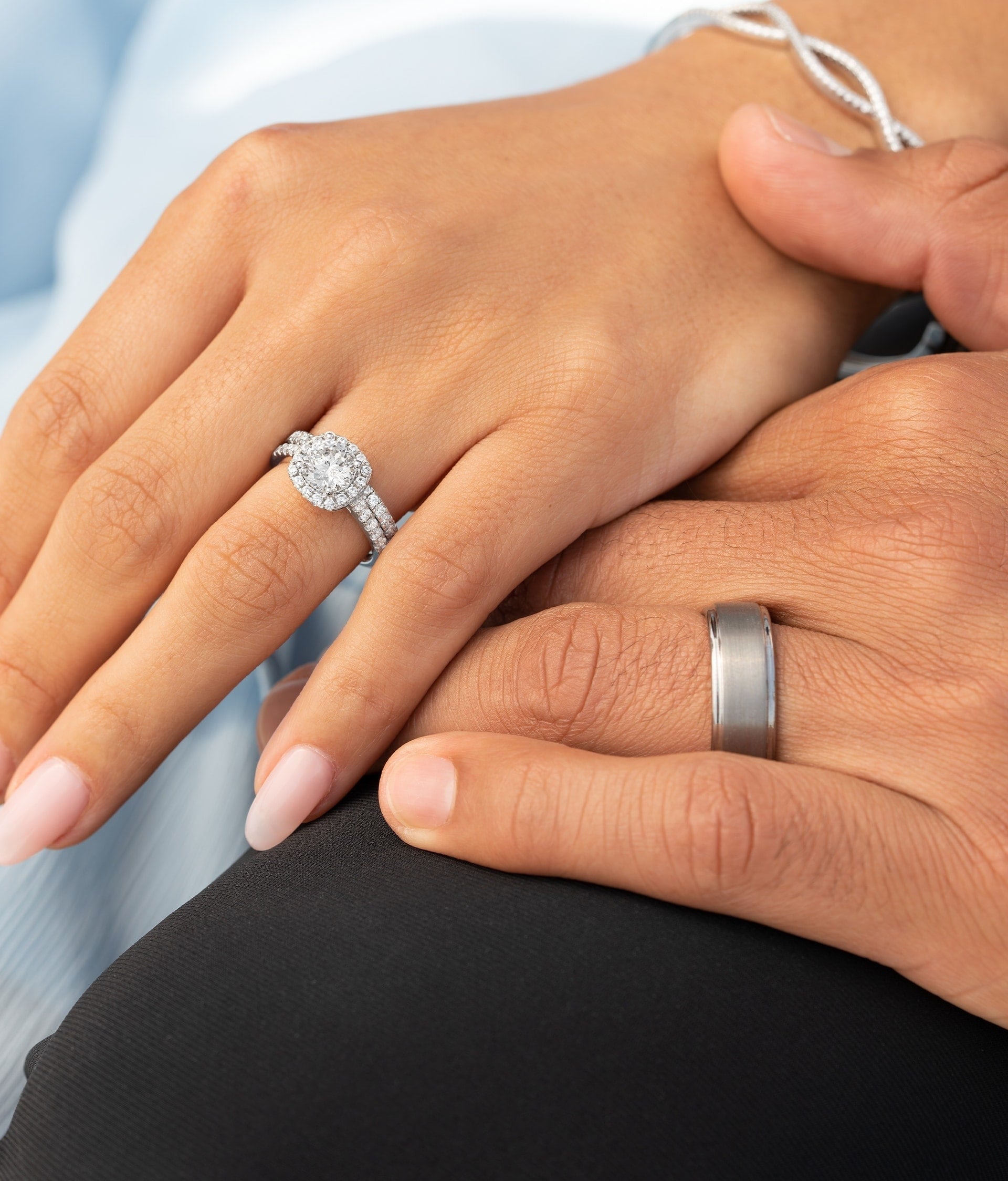 couple holding hand wearing silver men's ring and silver engagement ring