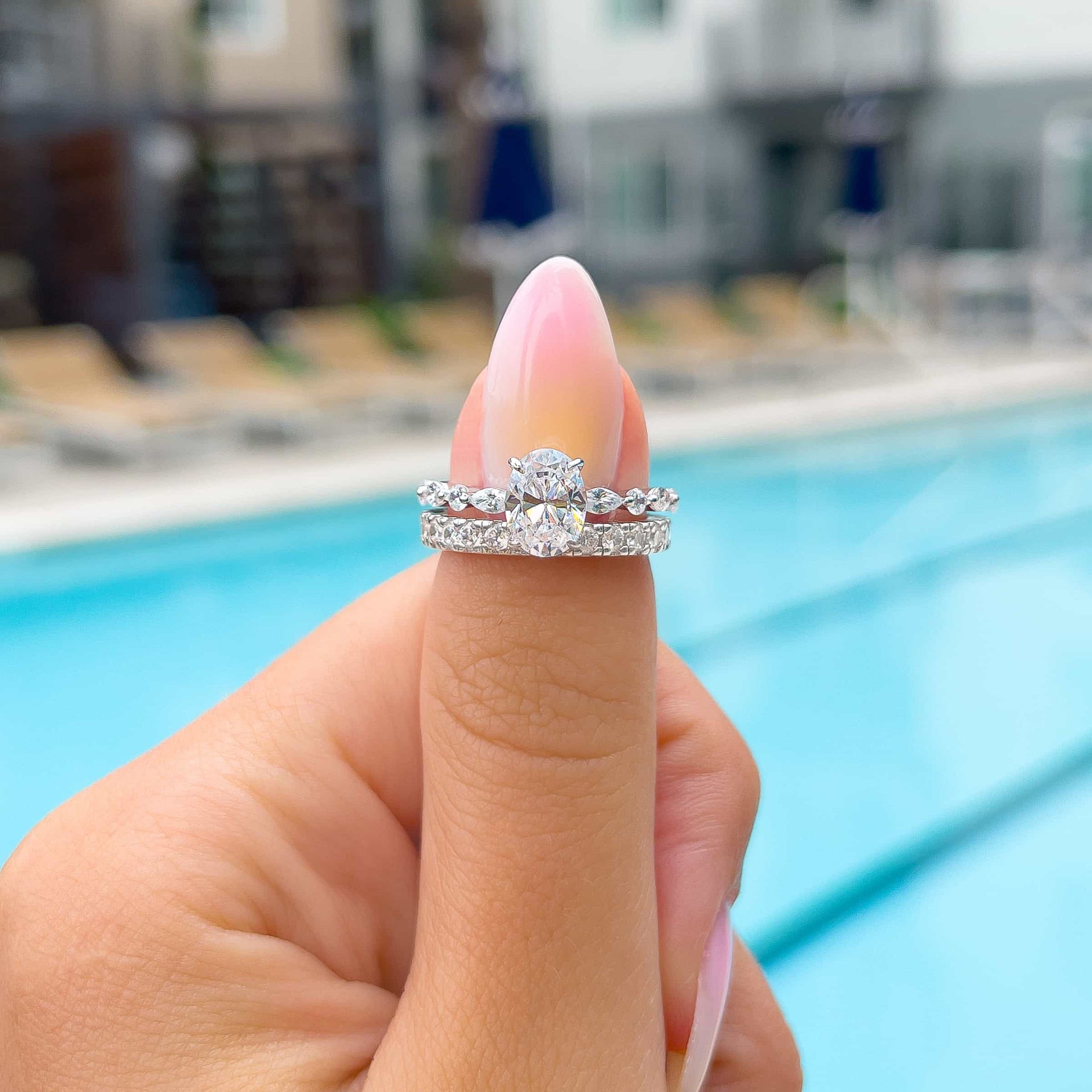 woman wearing silver engagement ring stack with eternity wedding band by pool