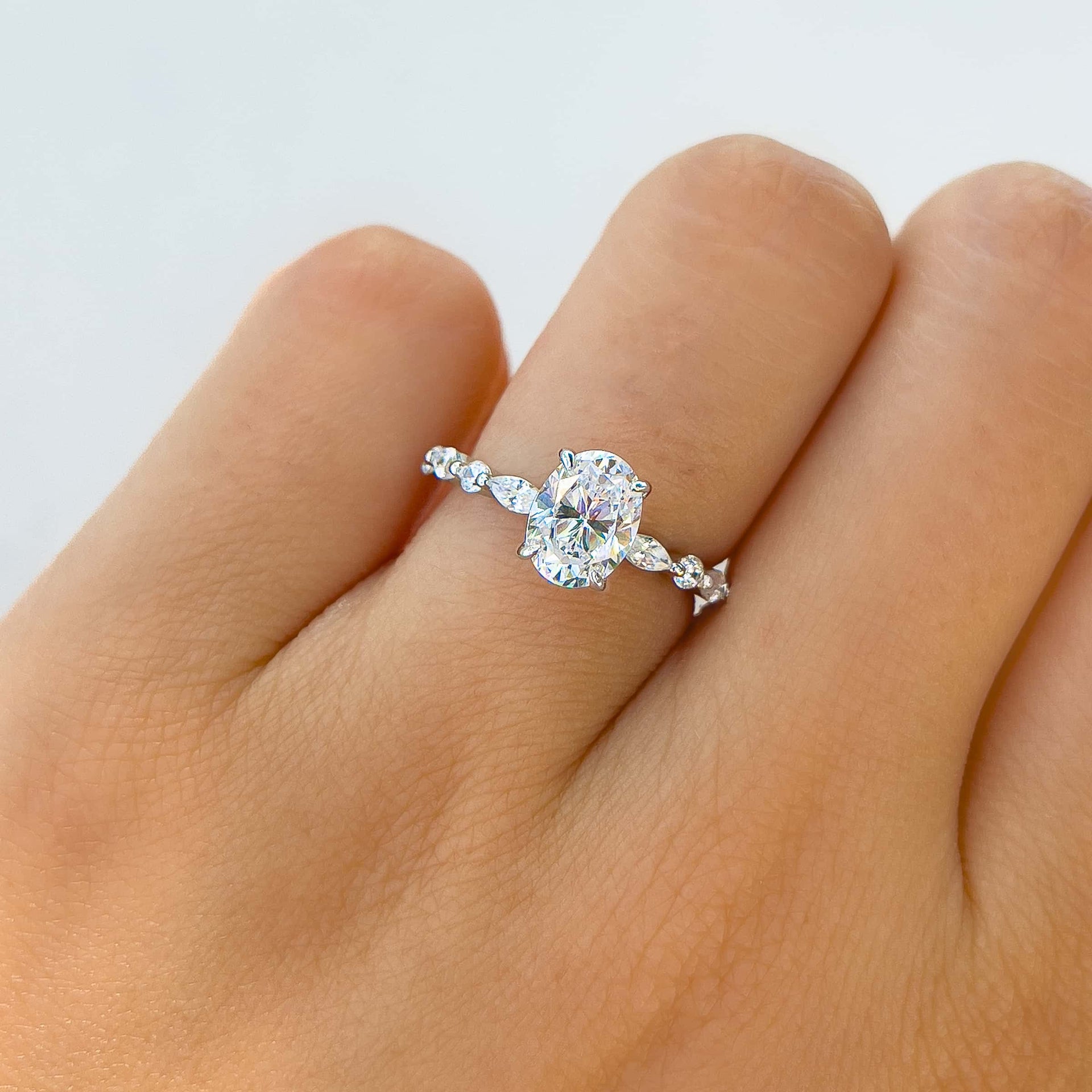 woman wearing gorgeous silver oval cut engagement ring with white wall