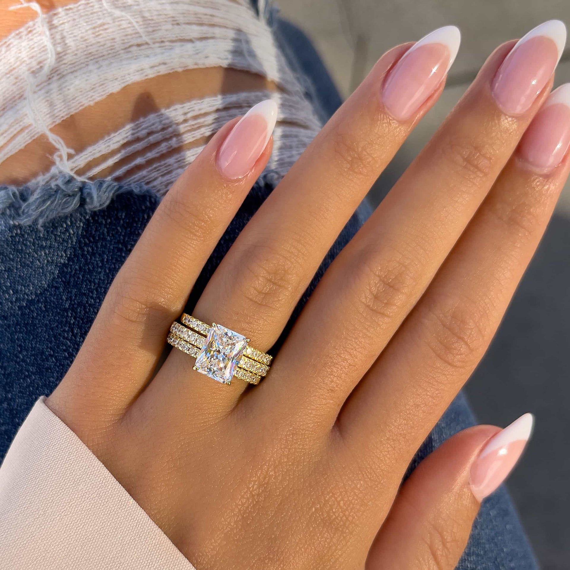 woman wearing two gold wedding bands and radiant cut engagement ring