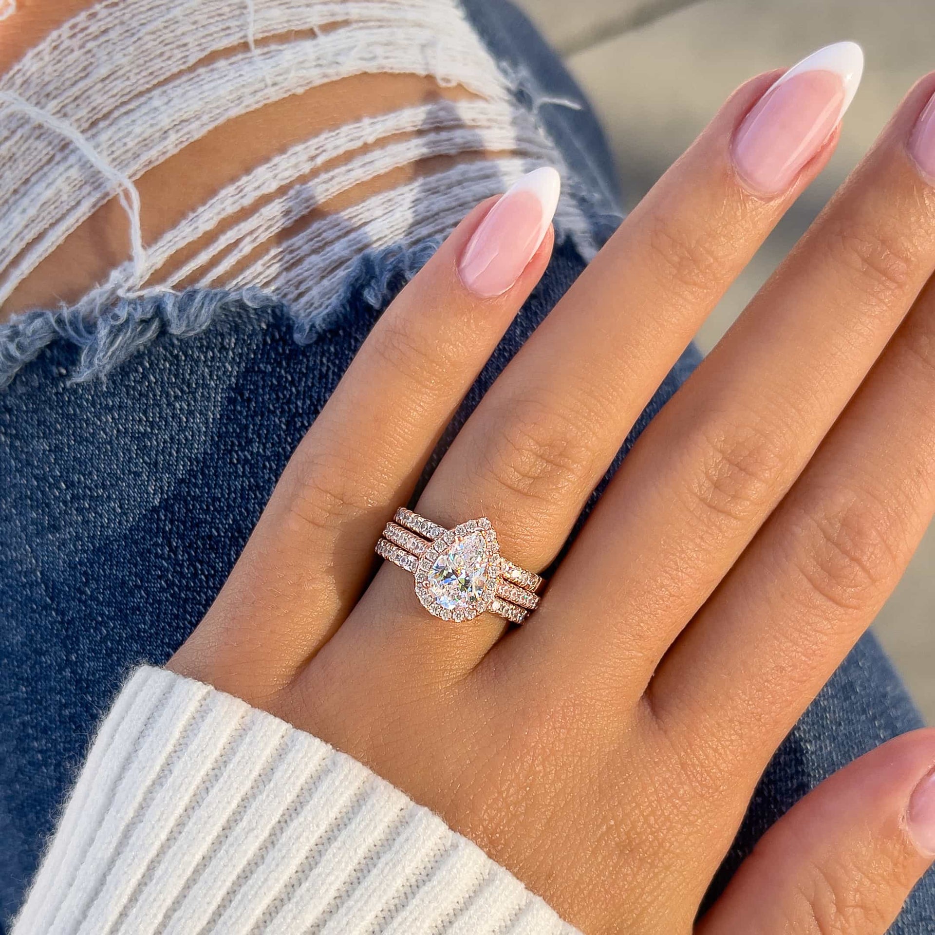 woman wearing rose gold stack with pear wedding ring and jeans