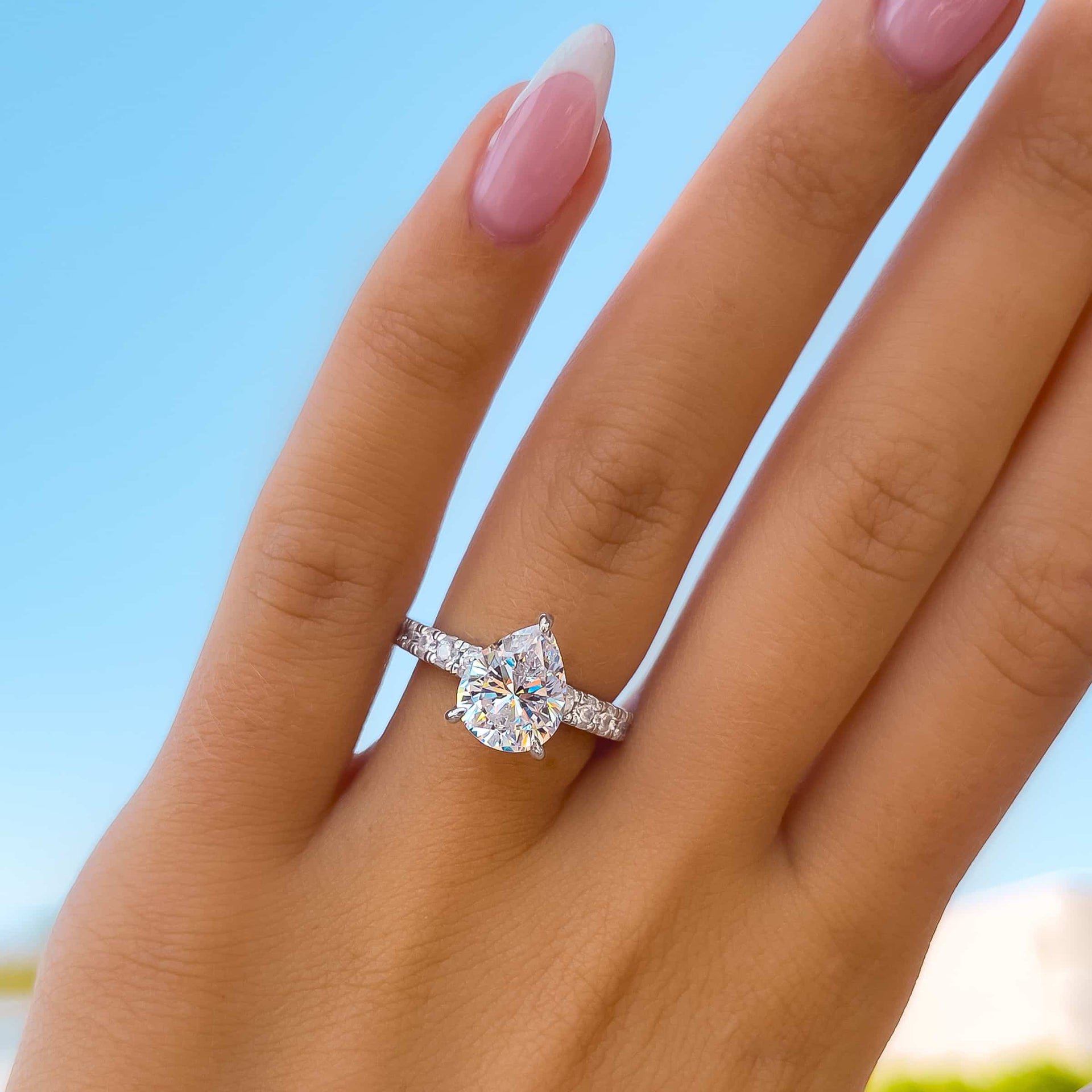 stunning silver 3 carat pear cut engagement ring on model with french tip nails