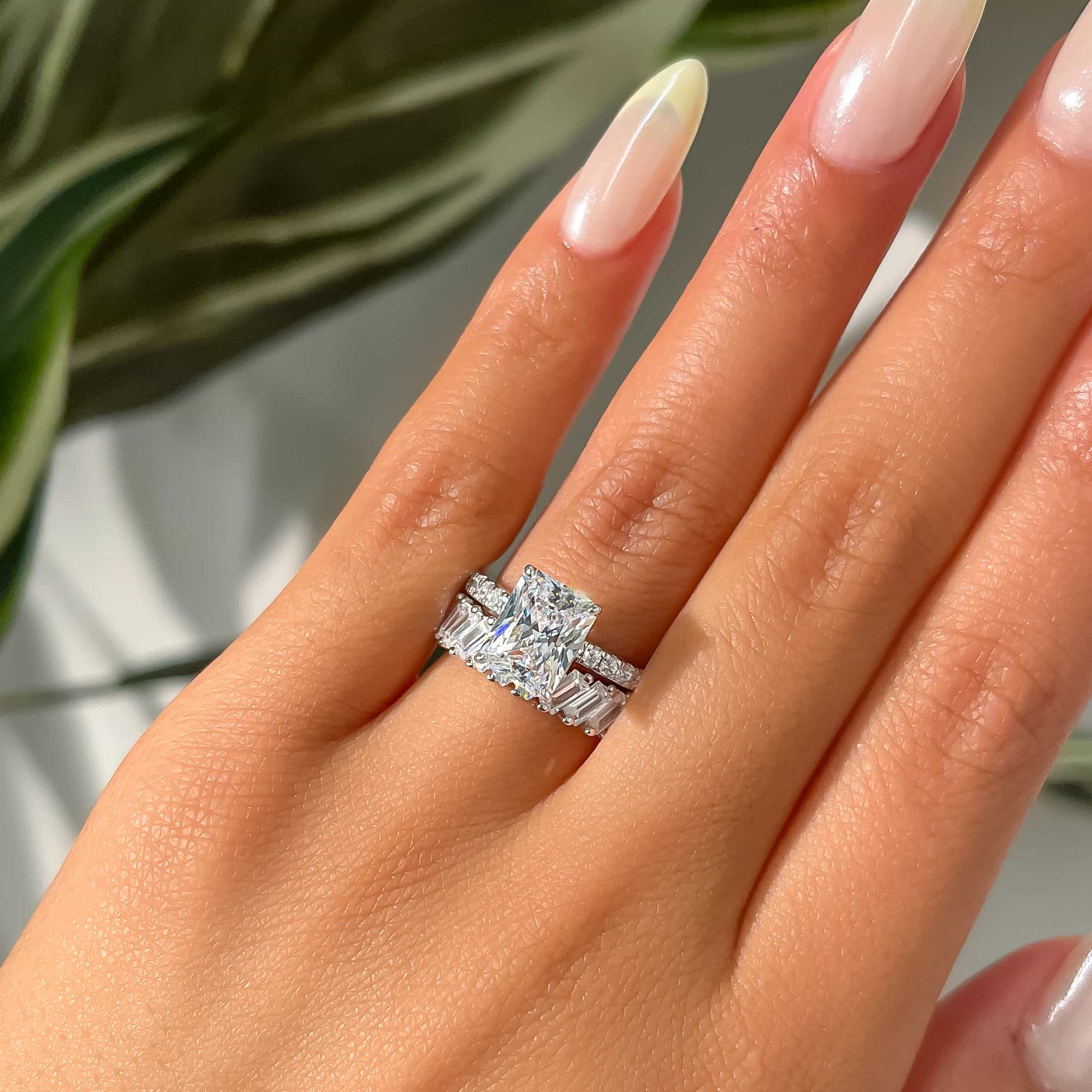 woman wearing radiant cut engagement ring with silver artemis wedding band with plant in background