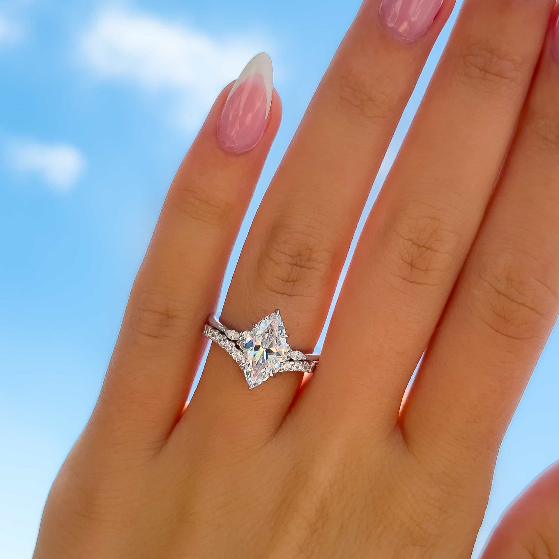 woman wearing gorgeous silver marquise engagement ring with chevron wedding band