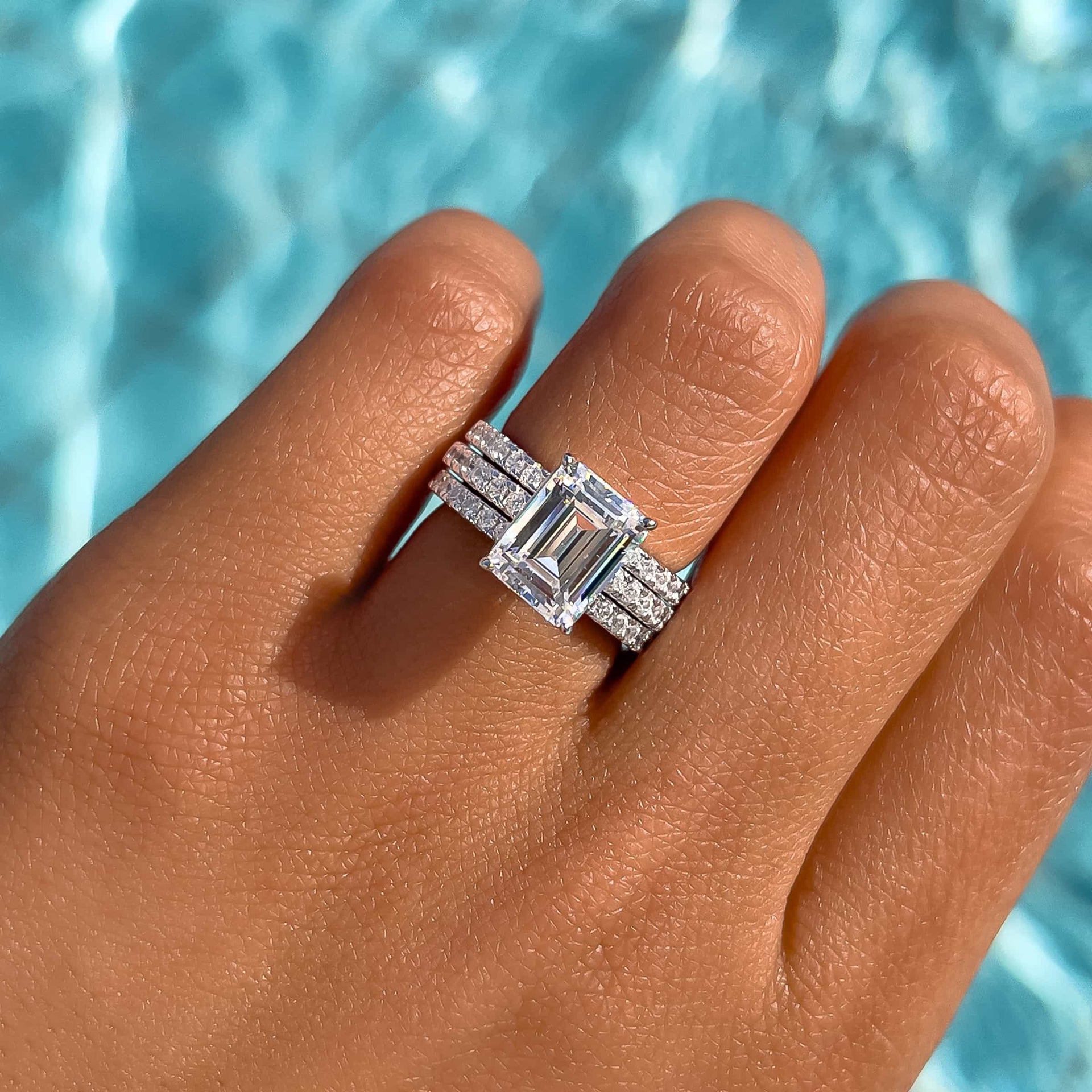 woman wearing stunning emerald cut wedding ring stack by pool in silver