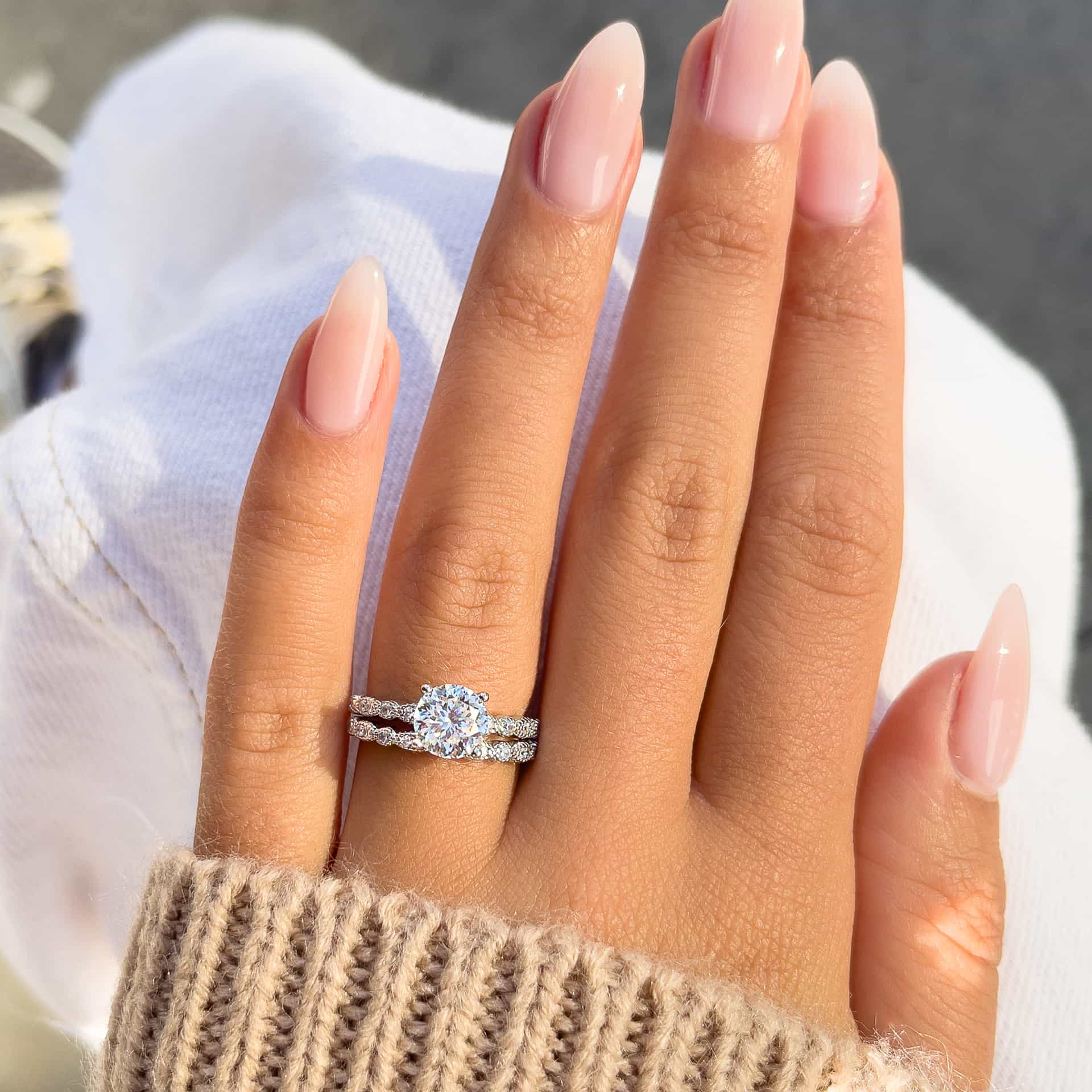 woman wearing beautiful silver round vintage engagement ring with brown sweater