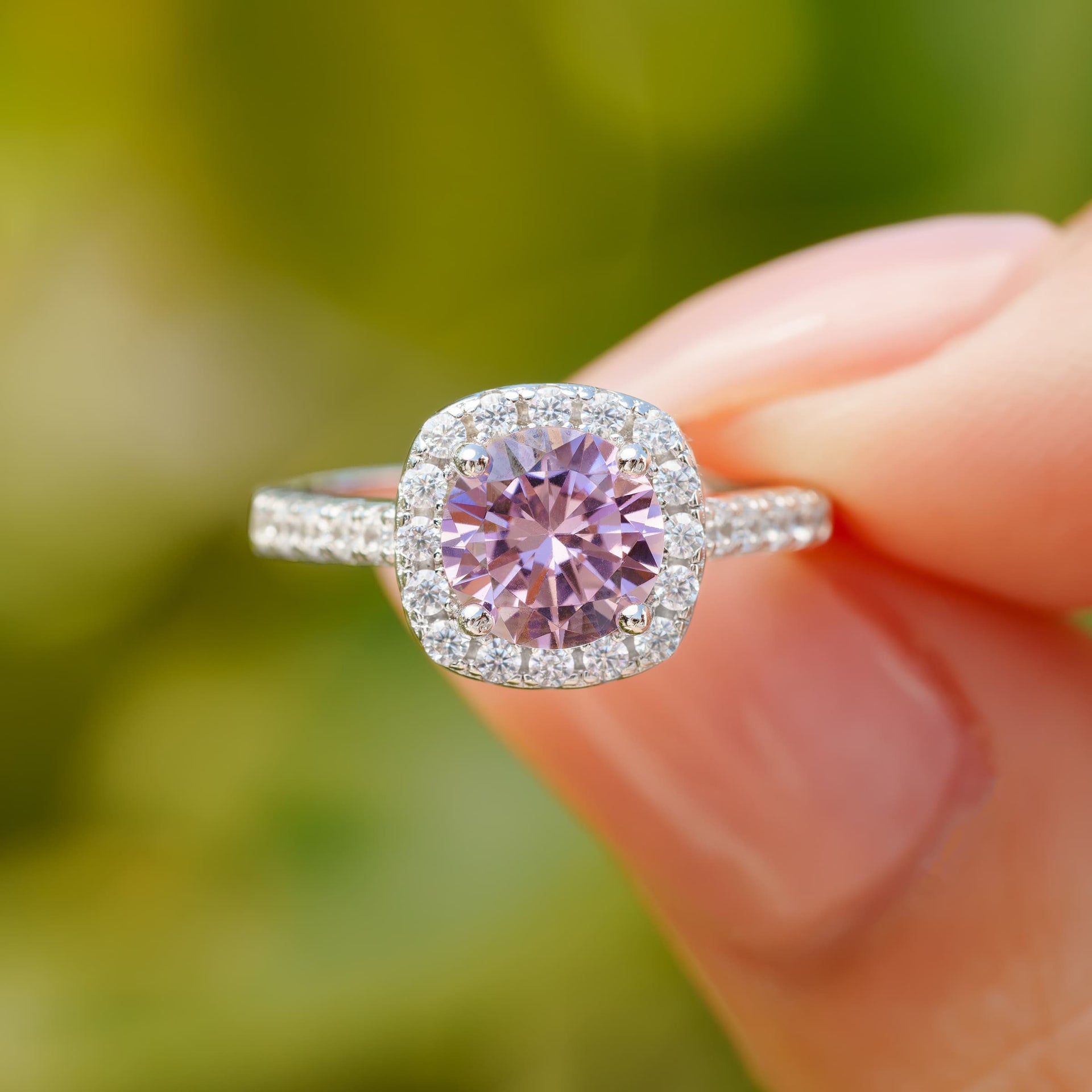 stunning halo pink engagement ring pinching with greenery in background