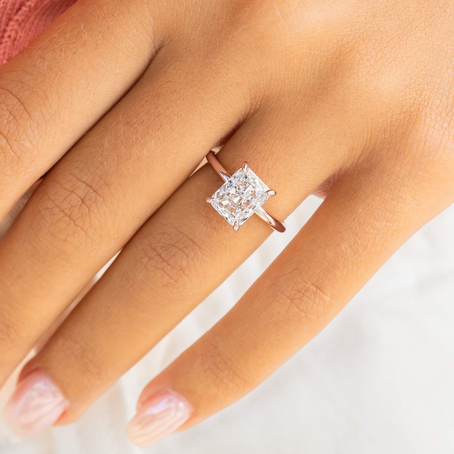 woman wearing rose gold radiant cut engagement ring with pink top