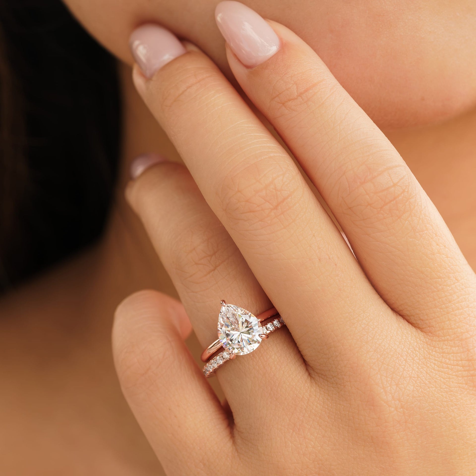 woman wearing pear shaped engagement ring with promise wedding band