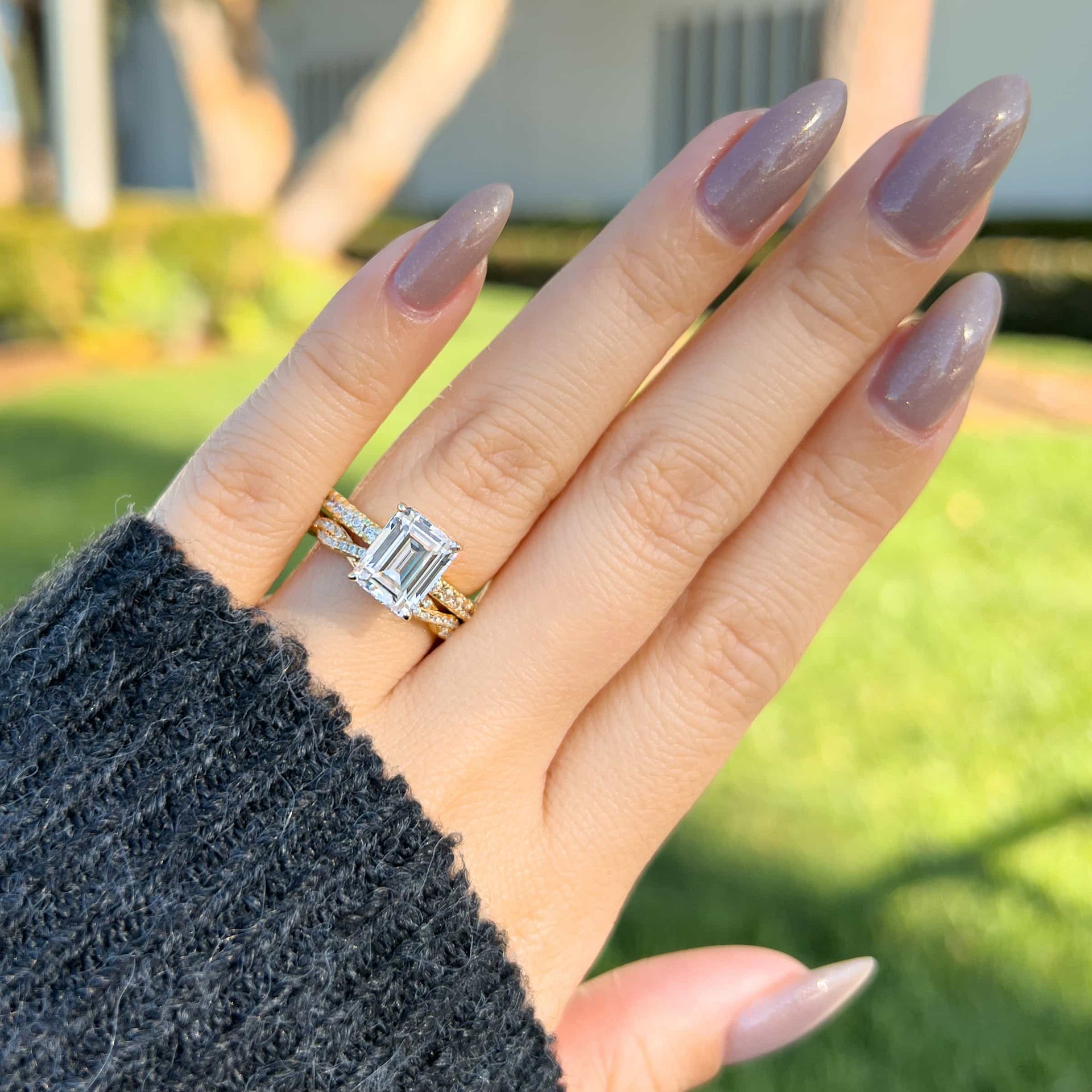 emerald cut engagement ring paired with gold twisted detail wedding band on female hand