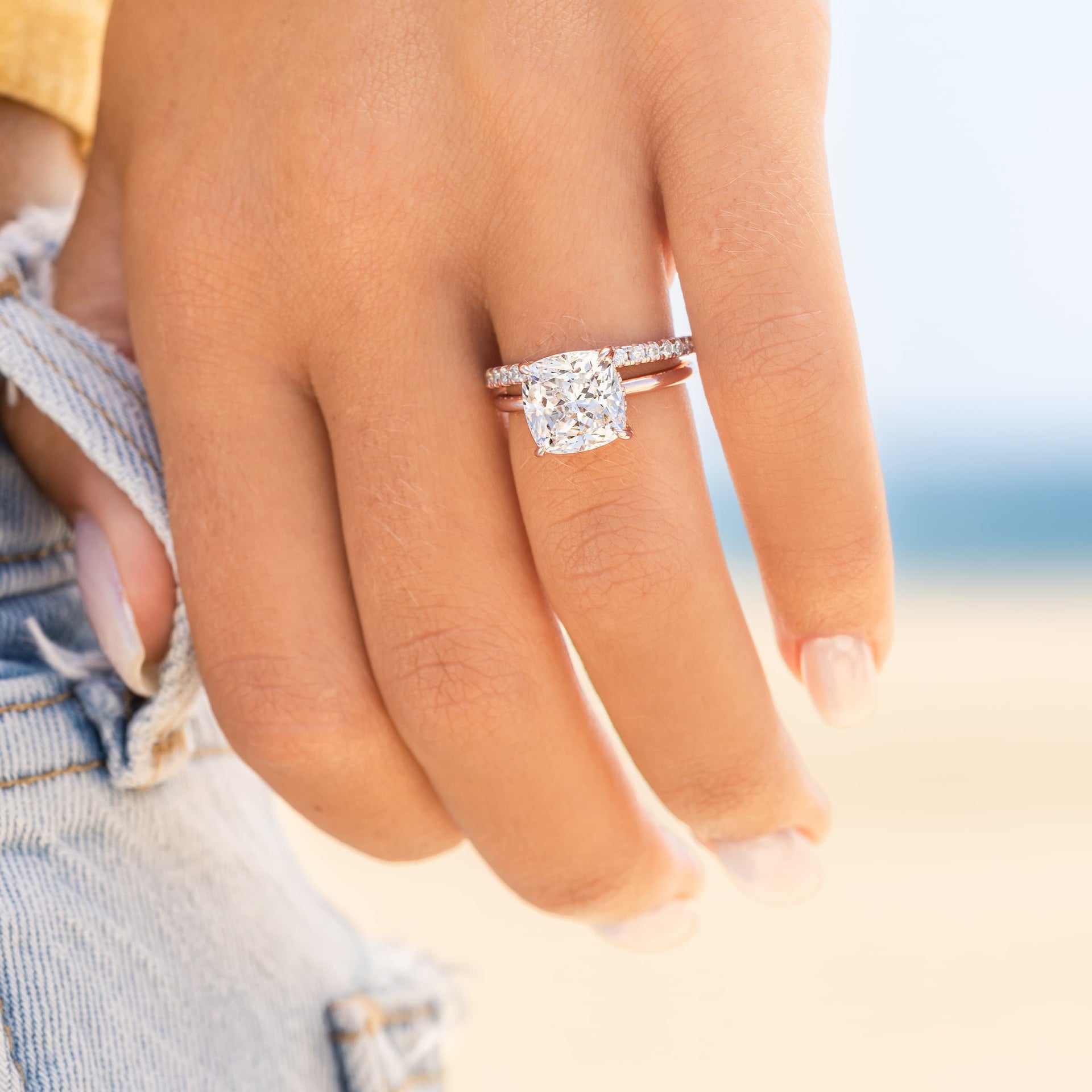 woman wearing rose gold promise wedding band with cushion cut engagement ring