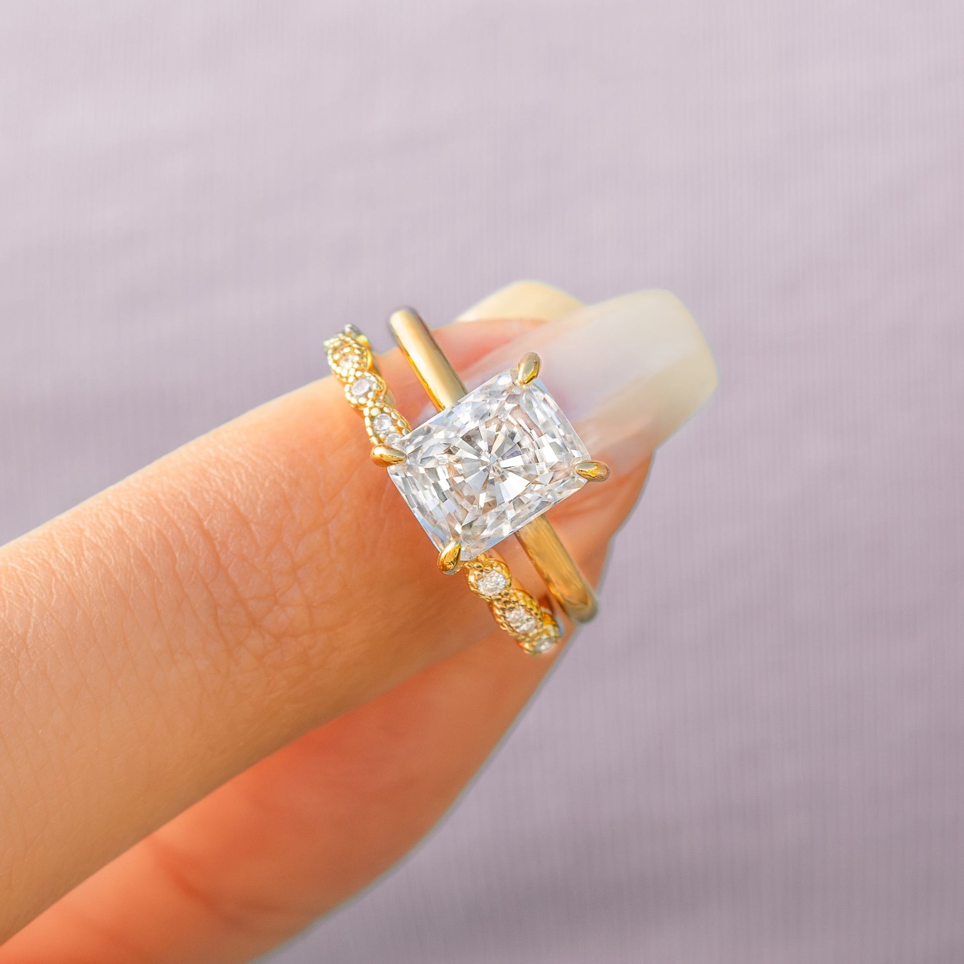 woman pinching gold engagement ring and wedding band