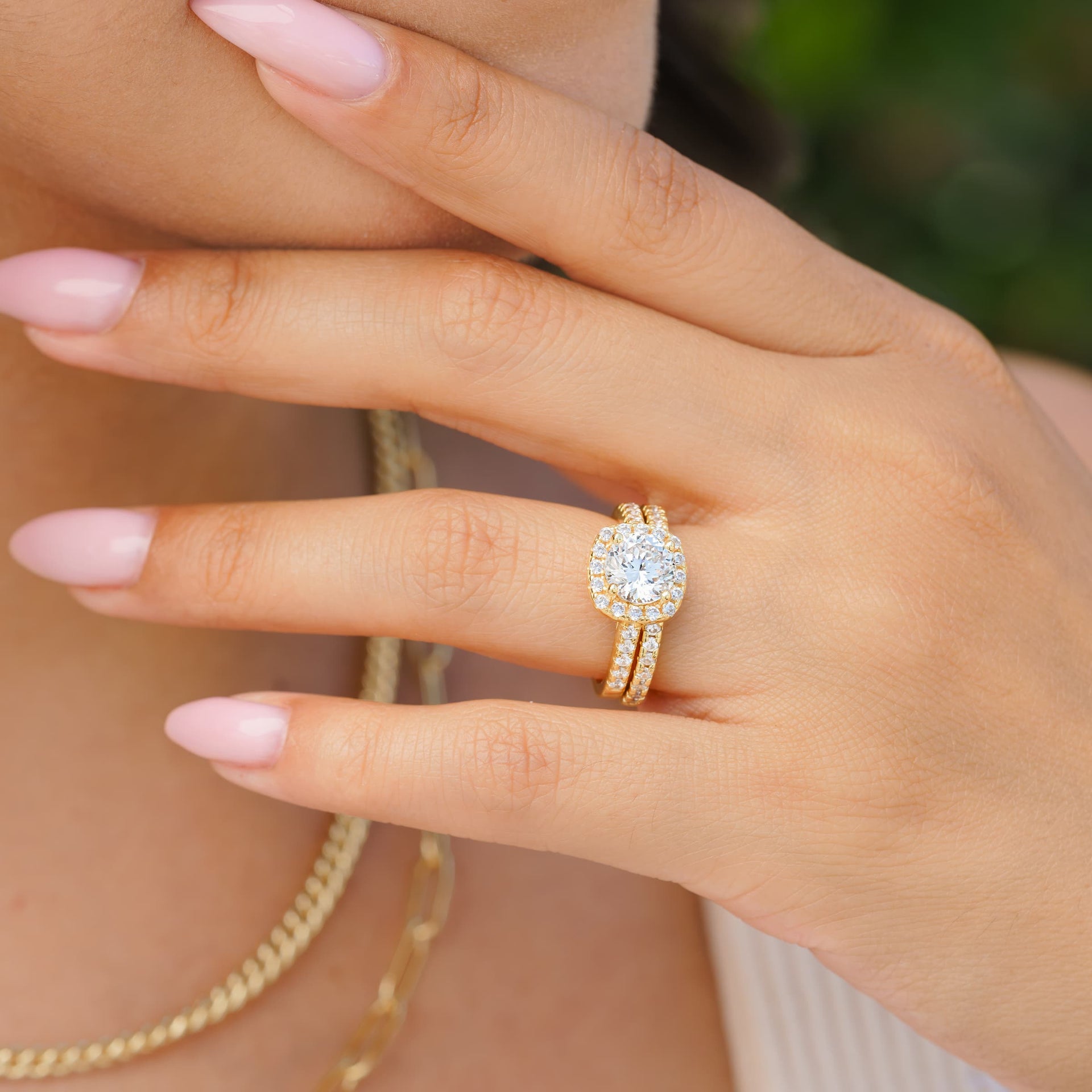 femal ehnad wearing gold cushion cut engagement ring with half eternity wedding band